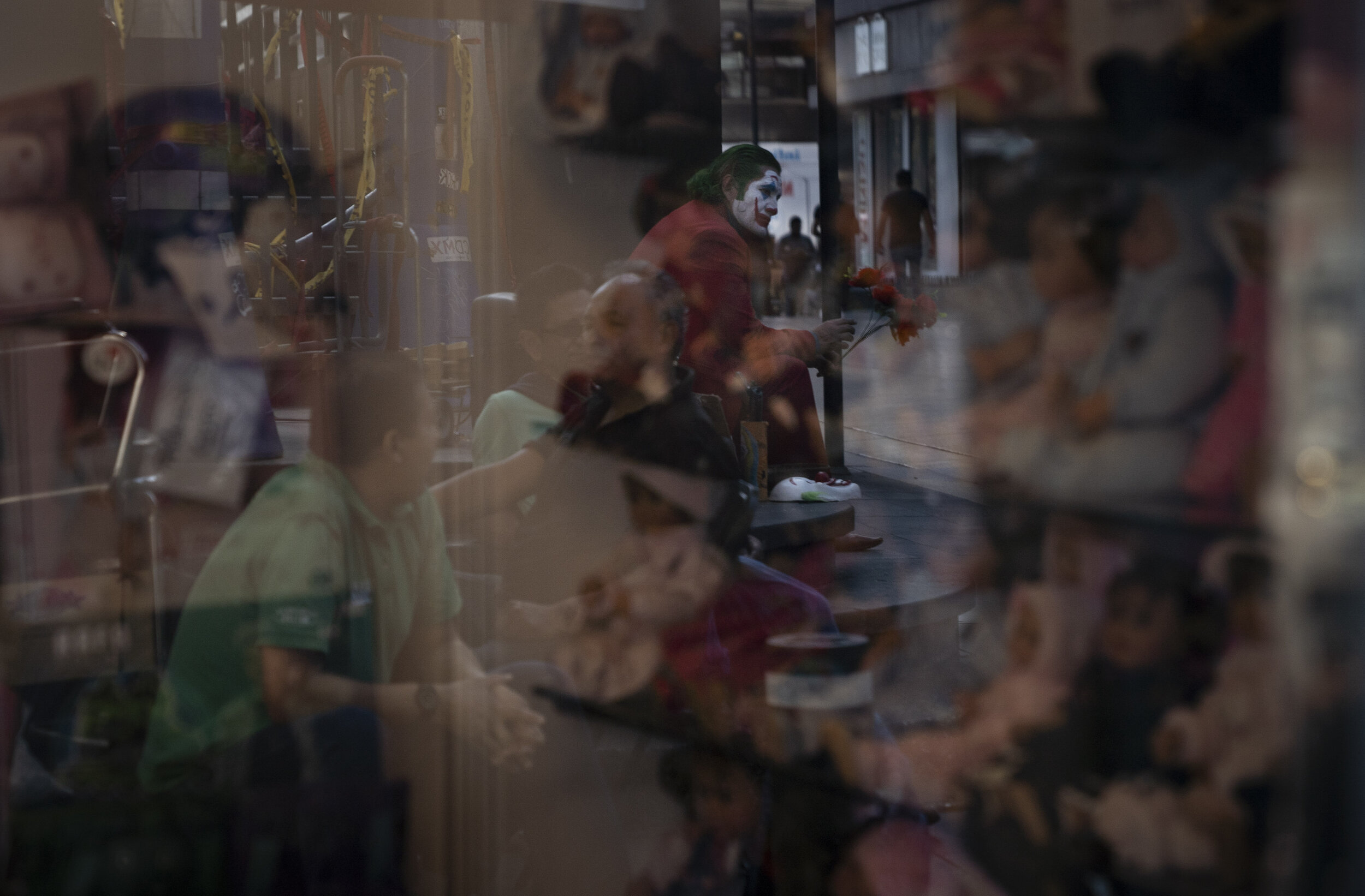   A man dressed as the Joker  is reflected on a store window during phase two of contingency measures.  