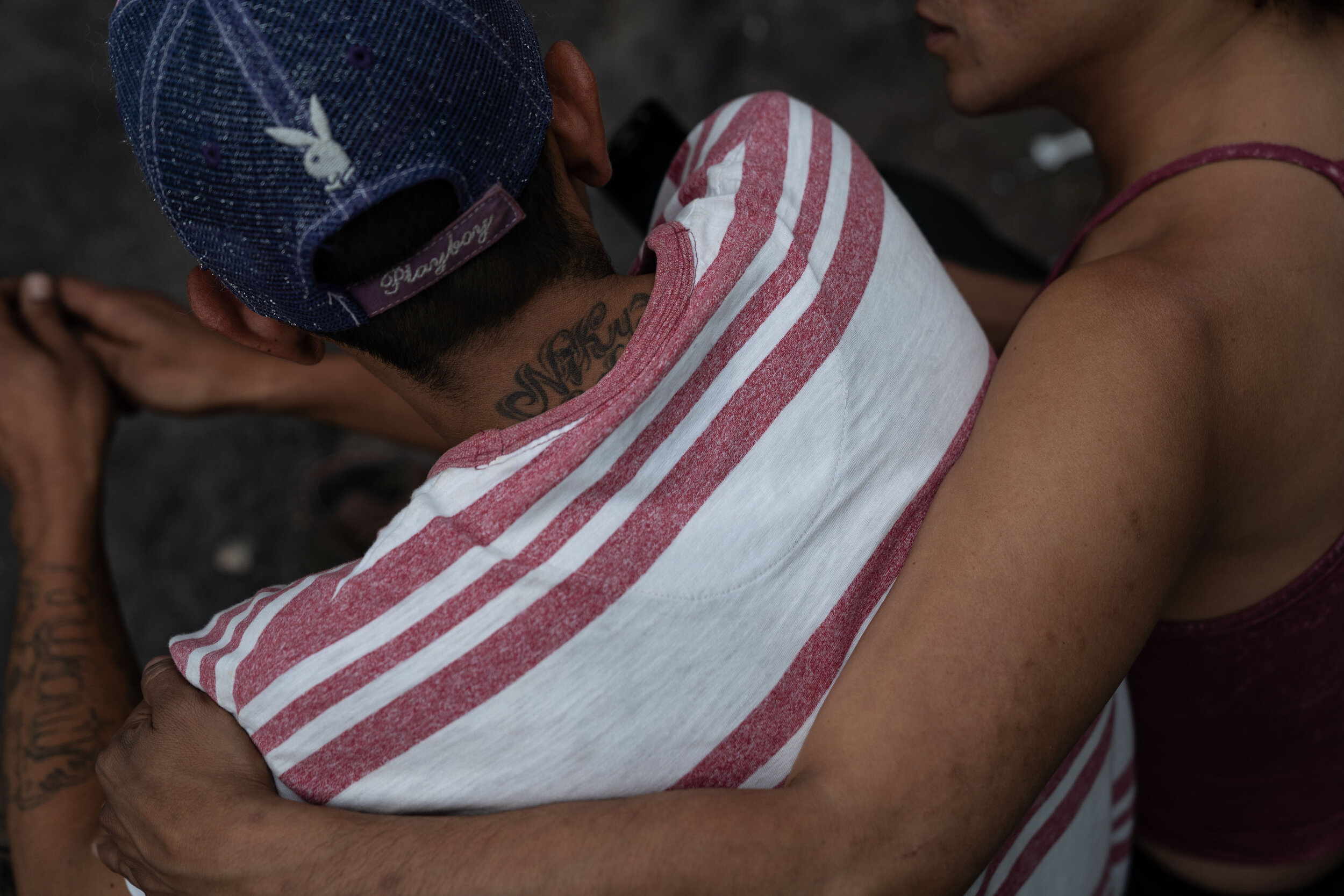   Nicky embraces Juan on a sidewalk in the Buenavista neighborhood.   