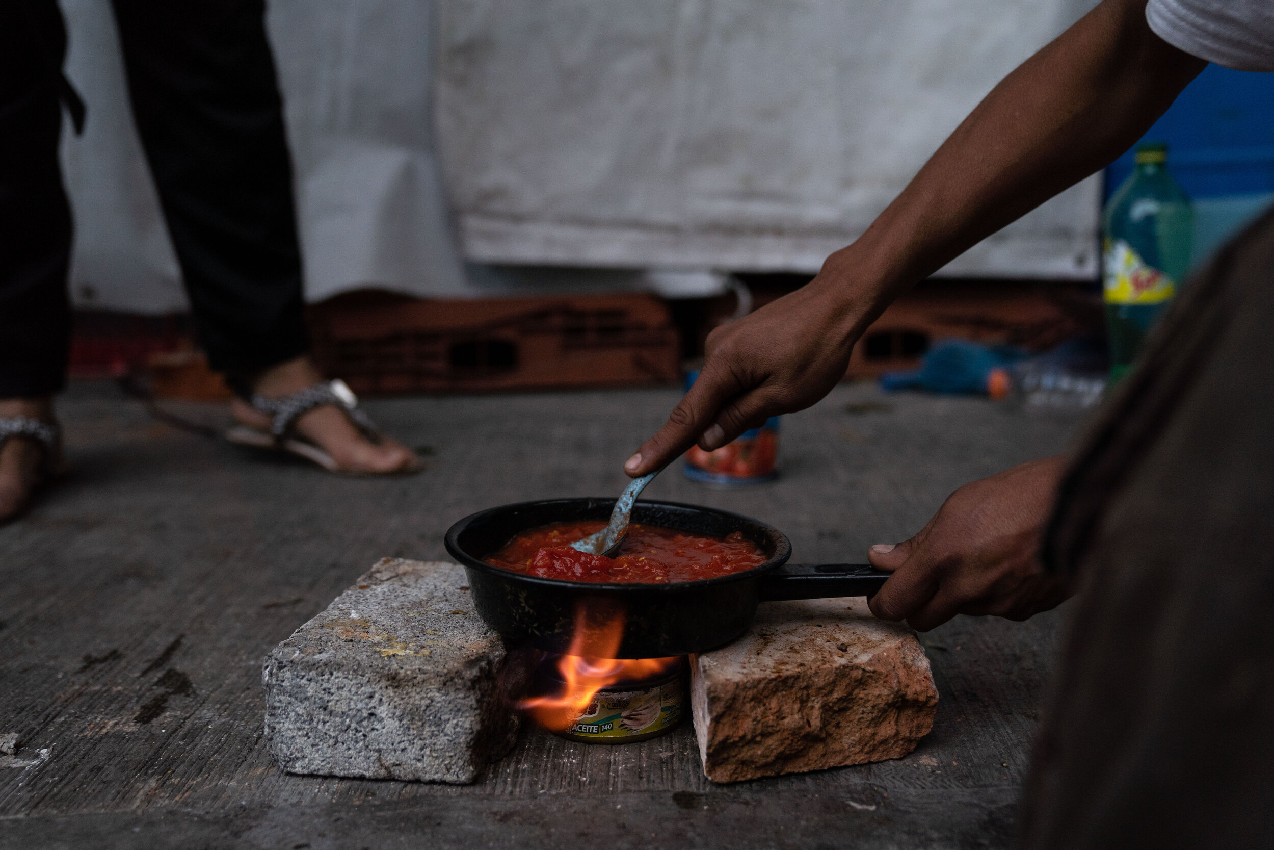   Juan cooks dinner on a sidewalk in the Buenavista neighborhood.   