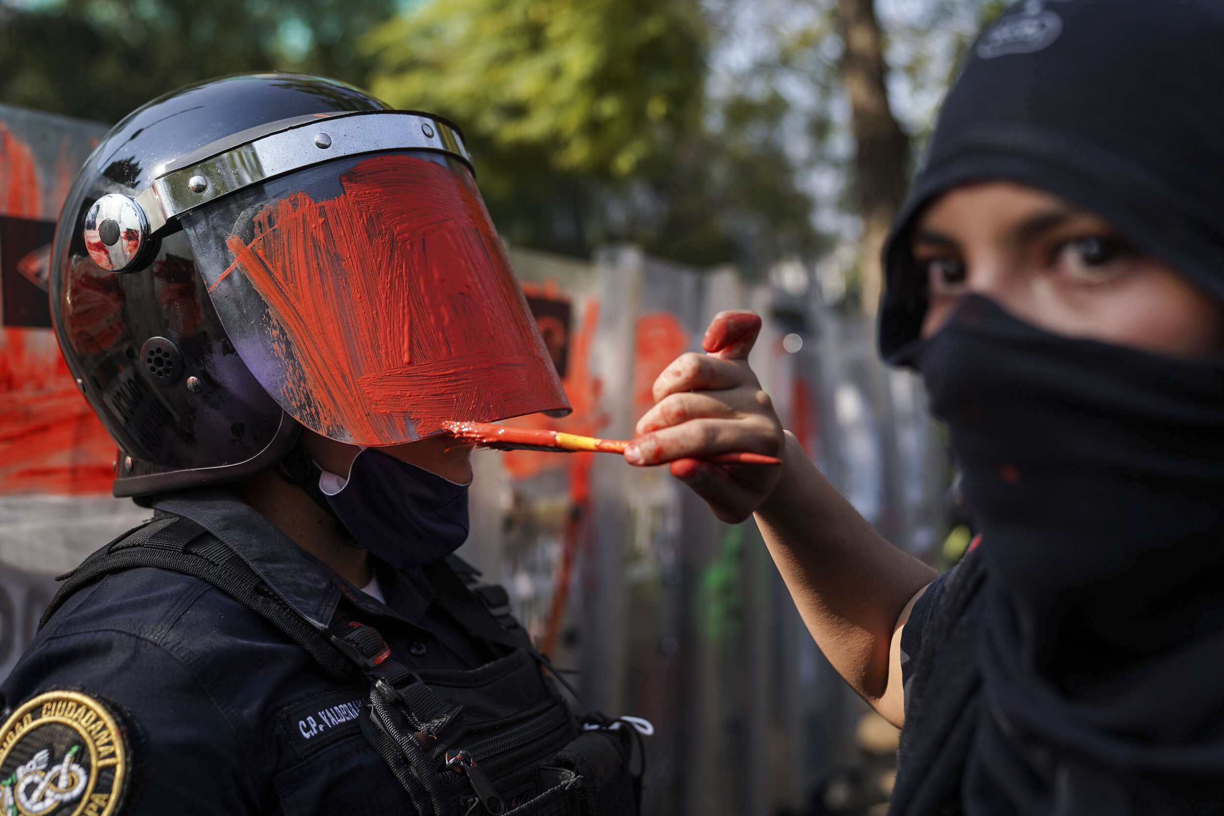   A member of a feminist collective paints the helmet of a riot police officer during a protest, Mexico City  