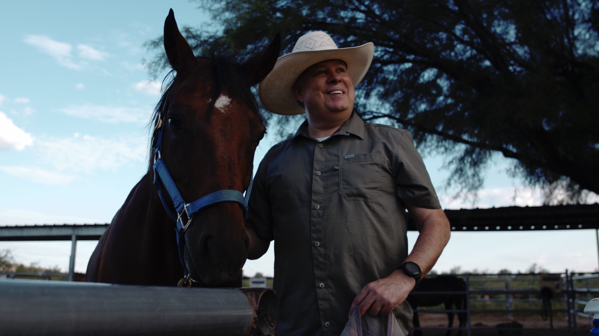 cowboy standing proudly with brown horse.png