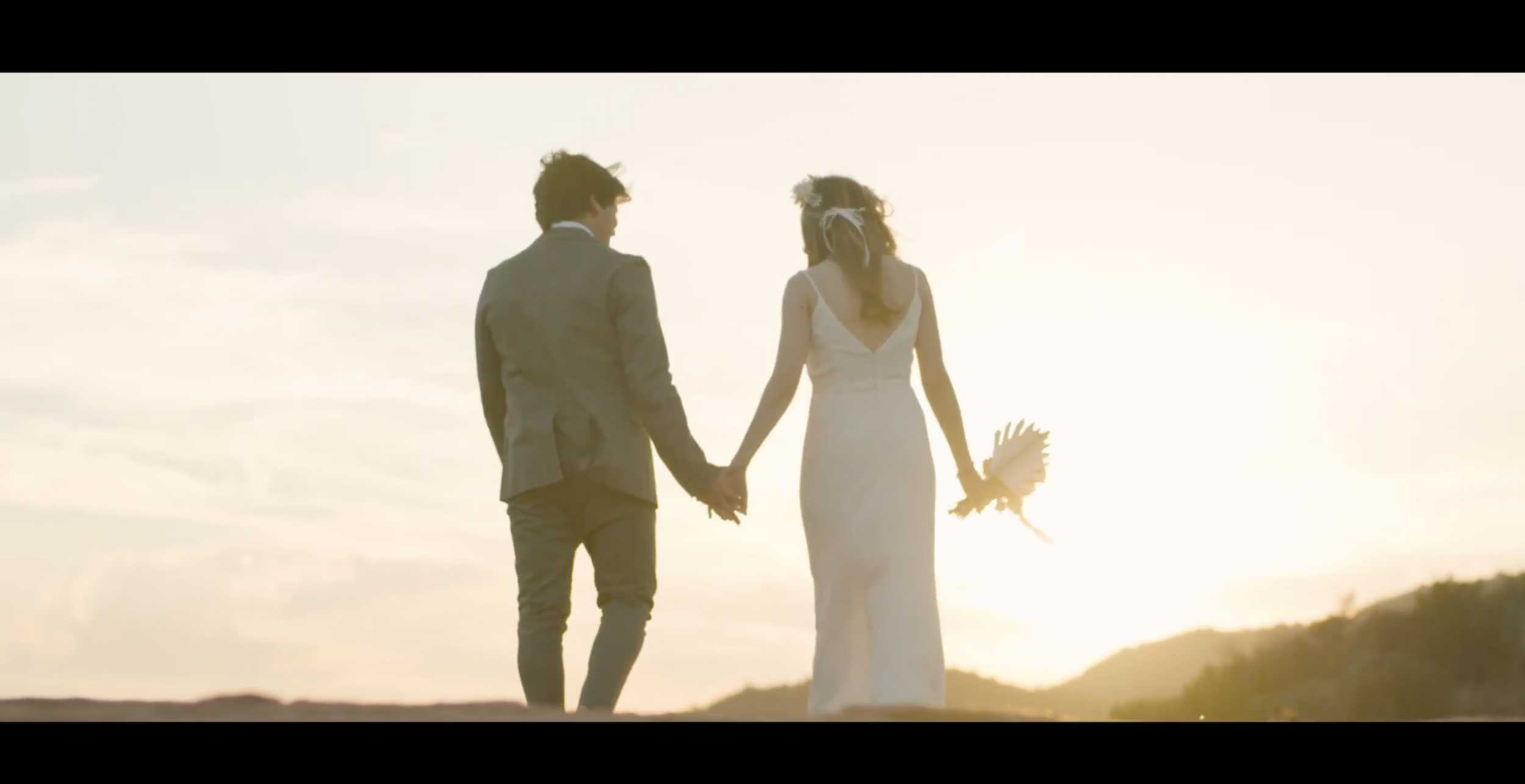 newly married couple walking towards sunset.png