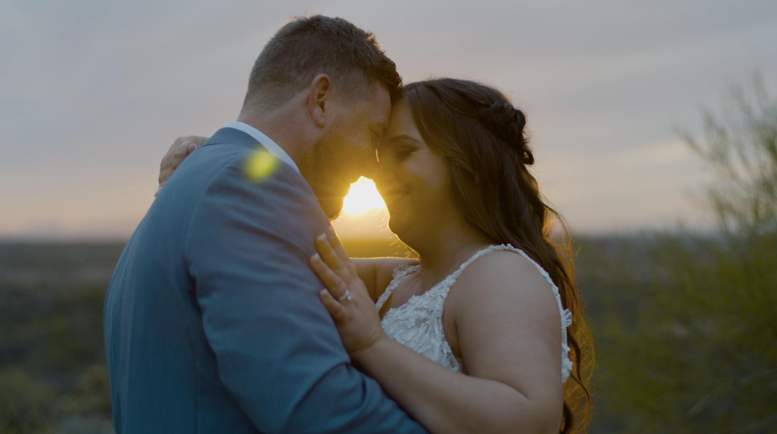 newly married couple embracing in front of sunset.png