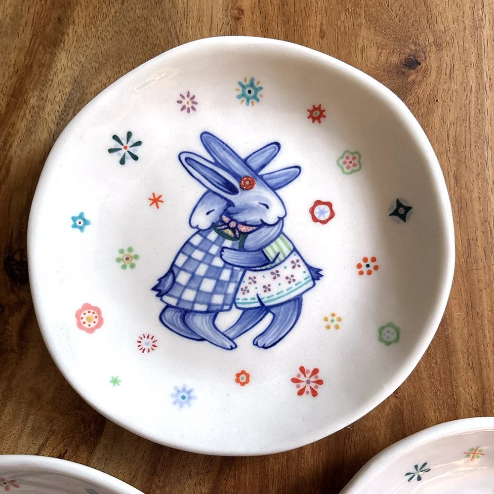 Bunnies hugging plates in porcelain