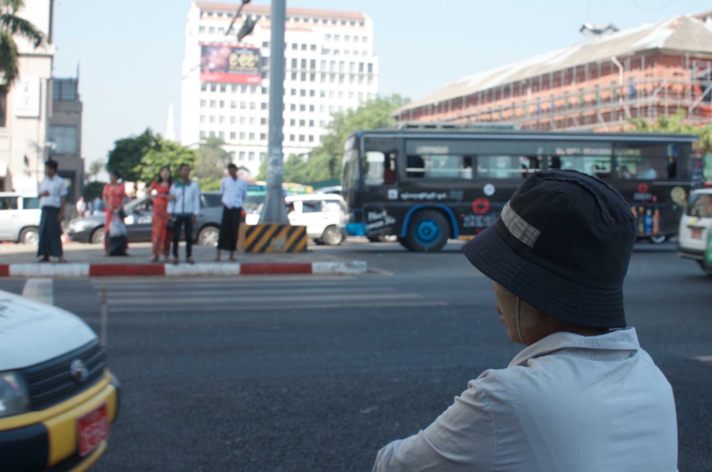 An old woman waiting to cross on the busy Bogyoke Aung San Road.