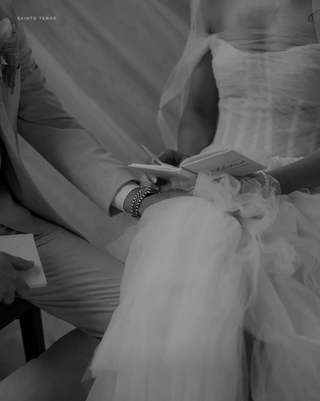 He's reading her words. She's reading his.
 
Sitting side by side in the quiet before the reception starts. Tulle everywhere. His hand resting on her knee. A vow book open in each lap.
 
This is the moment most people never see &mdash; before the act