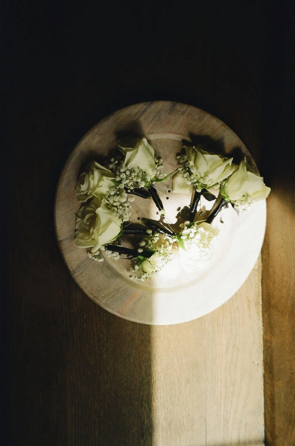 03-white-rose-boutonnieres-with-black-stem-wrap-in-a-wooden-bowl-at-the.jpg