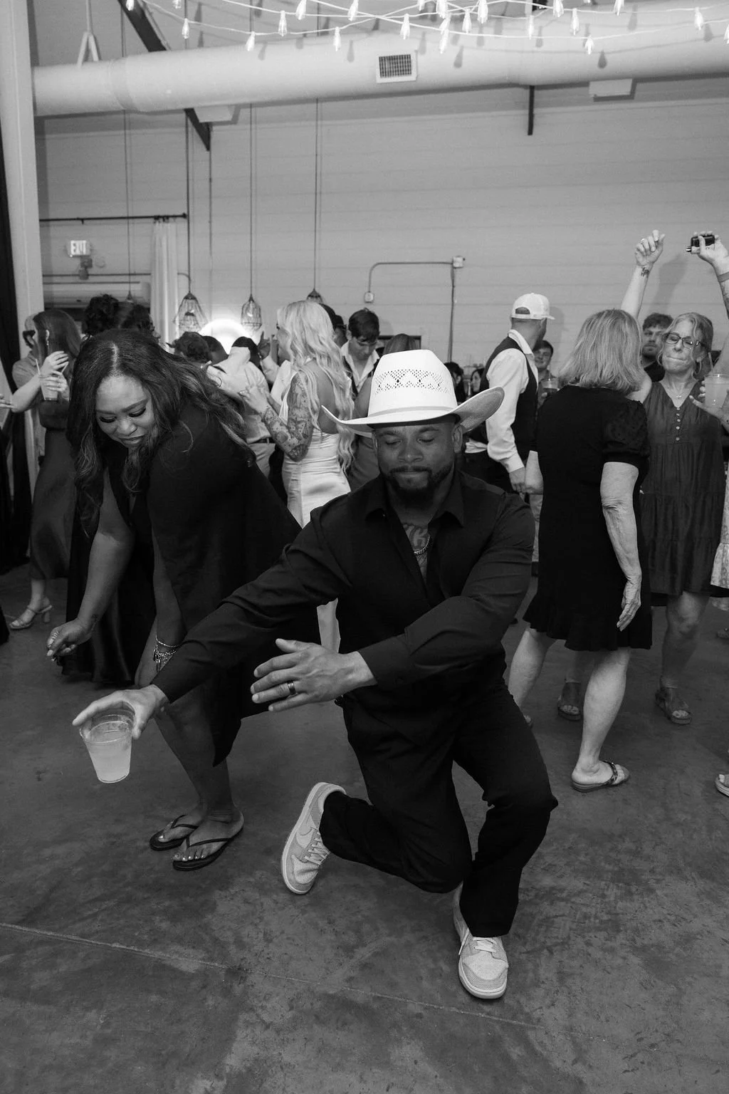 29-black-and-white-photograph-of-the-groom-dancing-in-a-white-cowboy-hat.jpg
