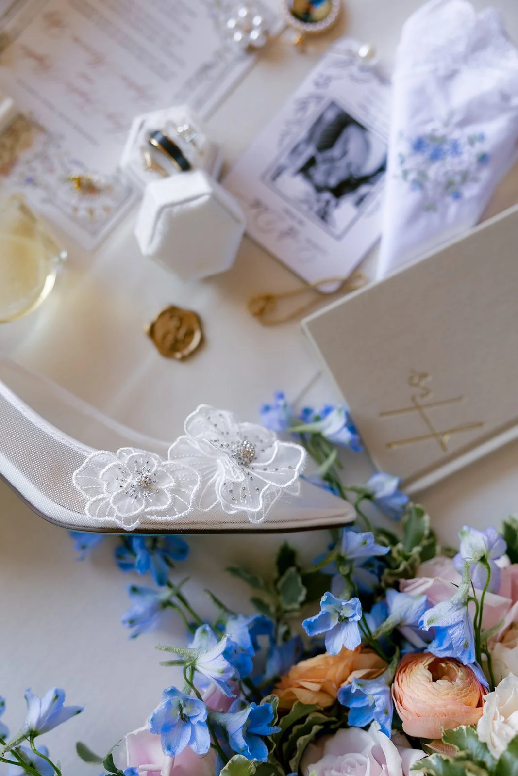 01-wedding-flat-lay-with-floral-appliqu-heels-rings-and-blue-delphinium-at.jpg