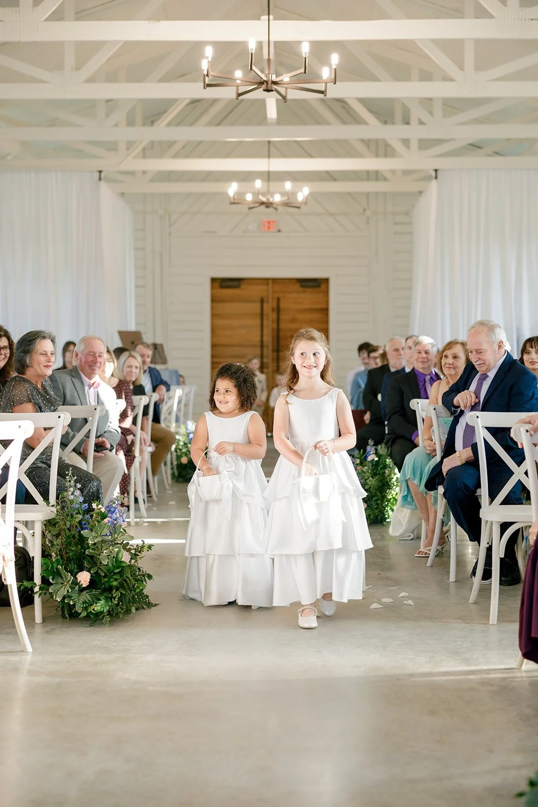 09-two-flower-girls-walking-down-the-aisle-of-the-white-chapel-at-the.jpg