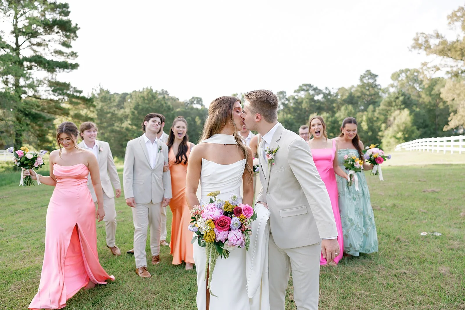 12-bride-and-groom-kissing-in-the-field-surrounded-by-their-wedding-party.jpg