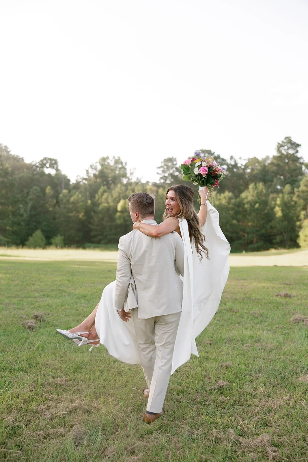 13-groom-carrying-the-bride-through-the-field-at-sunset-at-the-stables-at.jpg