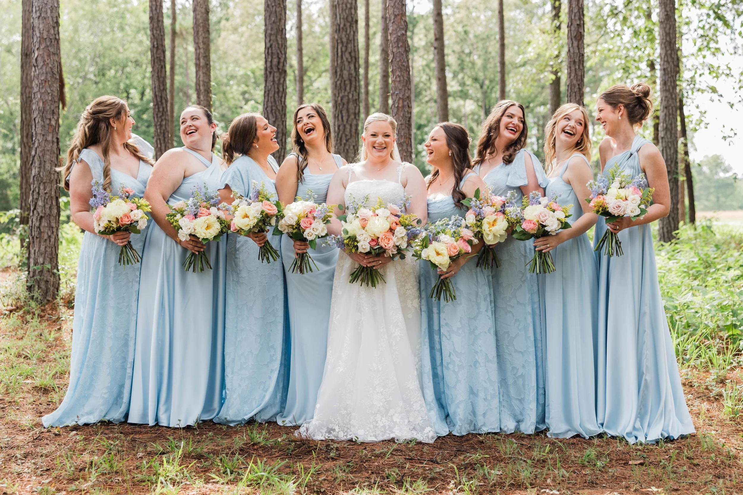 04-eight-bridesmaids-in-light-blue-with-pastel-bouquets-in-the-pines-at.jpg