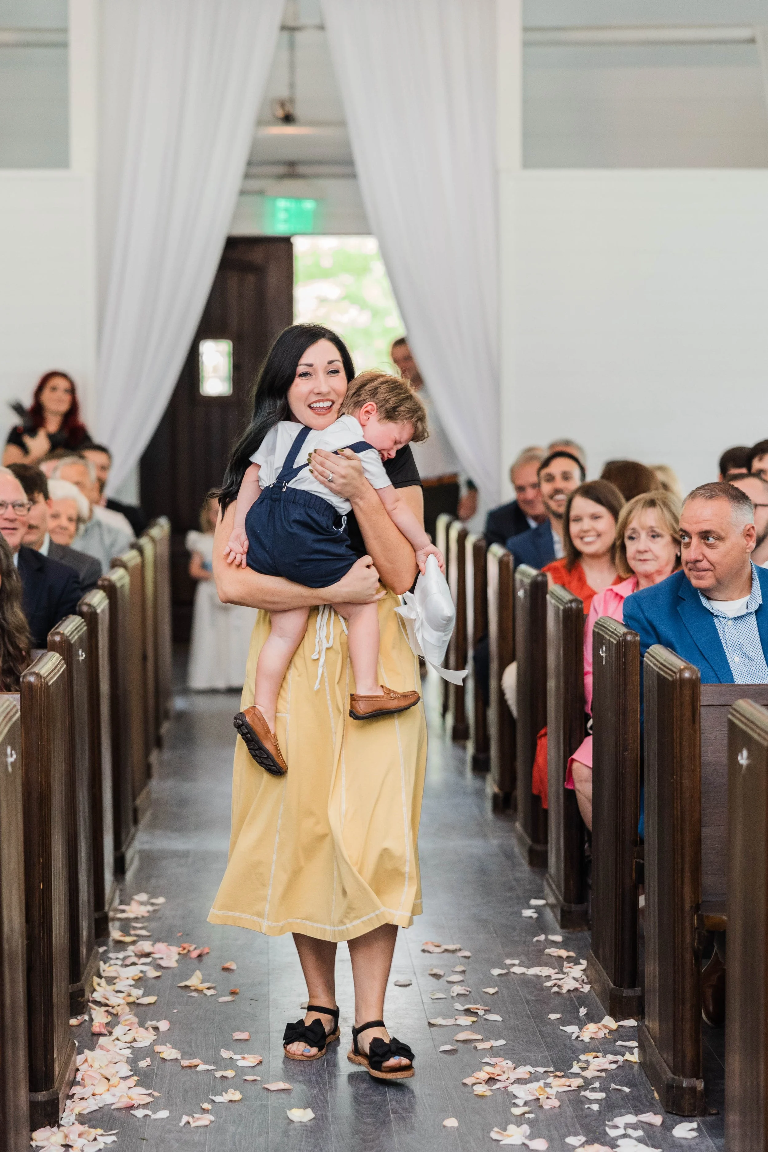 05-ring-bearer-carried-down-the-petal-strewn-aisle-of-the-chapel-at-the.jpg