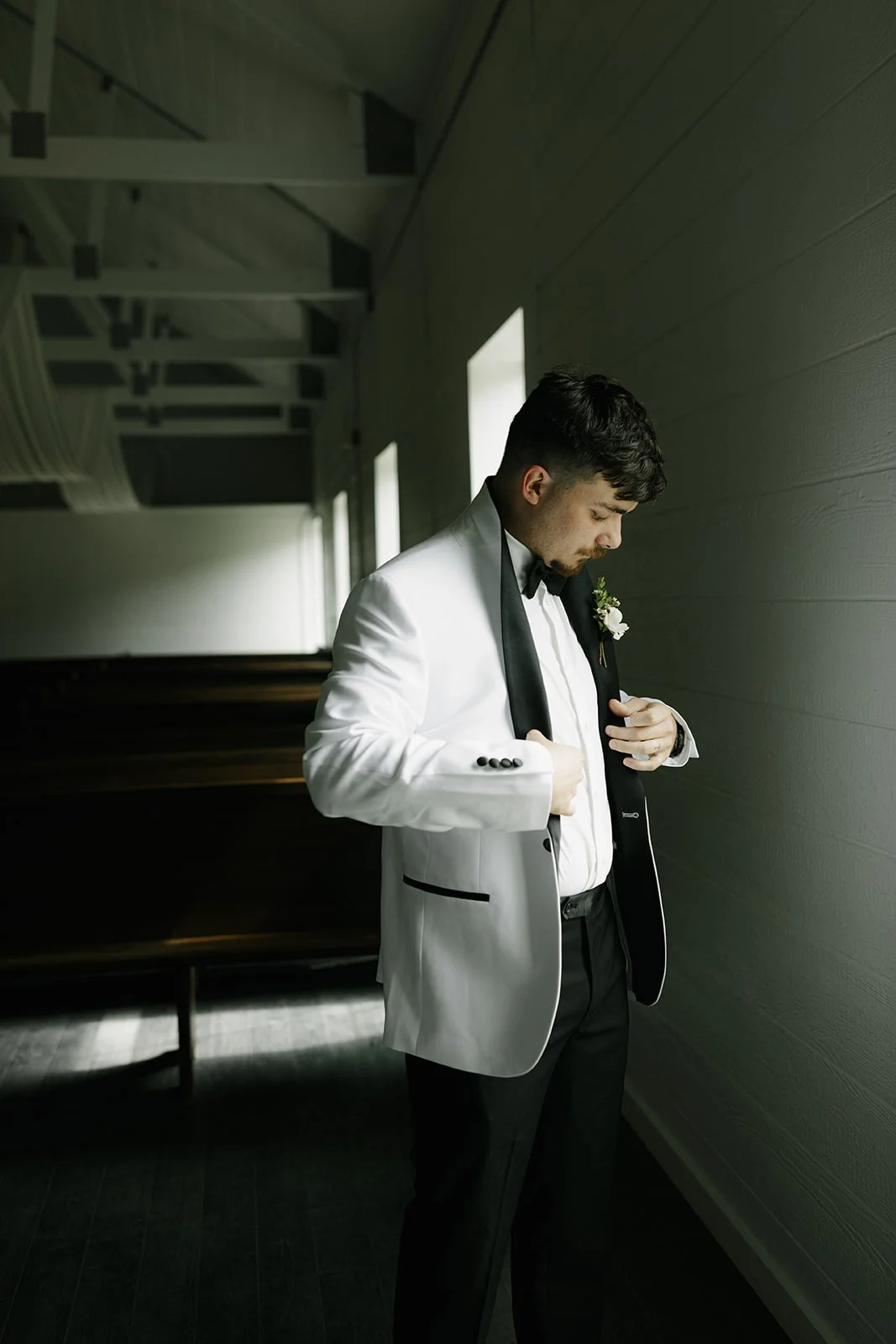 08-groom-in-a-white-dinner-jacket-in-the-chapel-with-dark-wooden-pews-at.jpg
