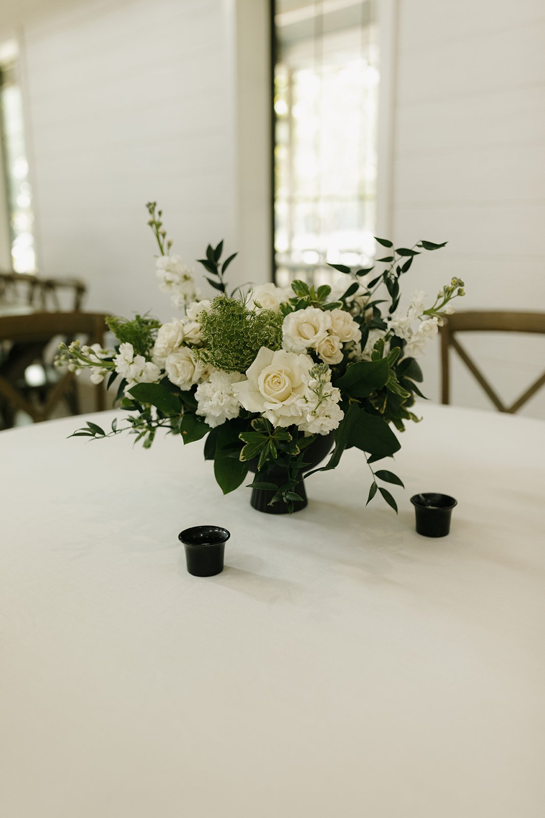 19-white-rose-centerpiece-in-a-black-footed-bowl-with-black-votives-at-the.jpg