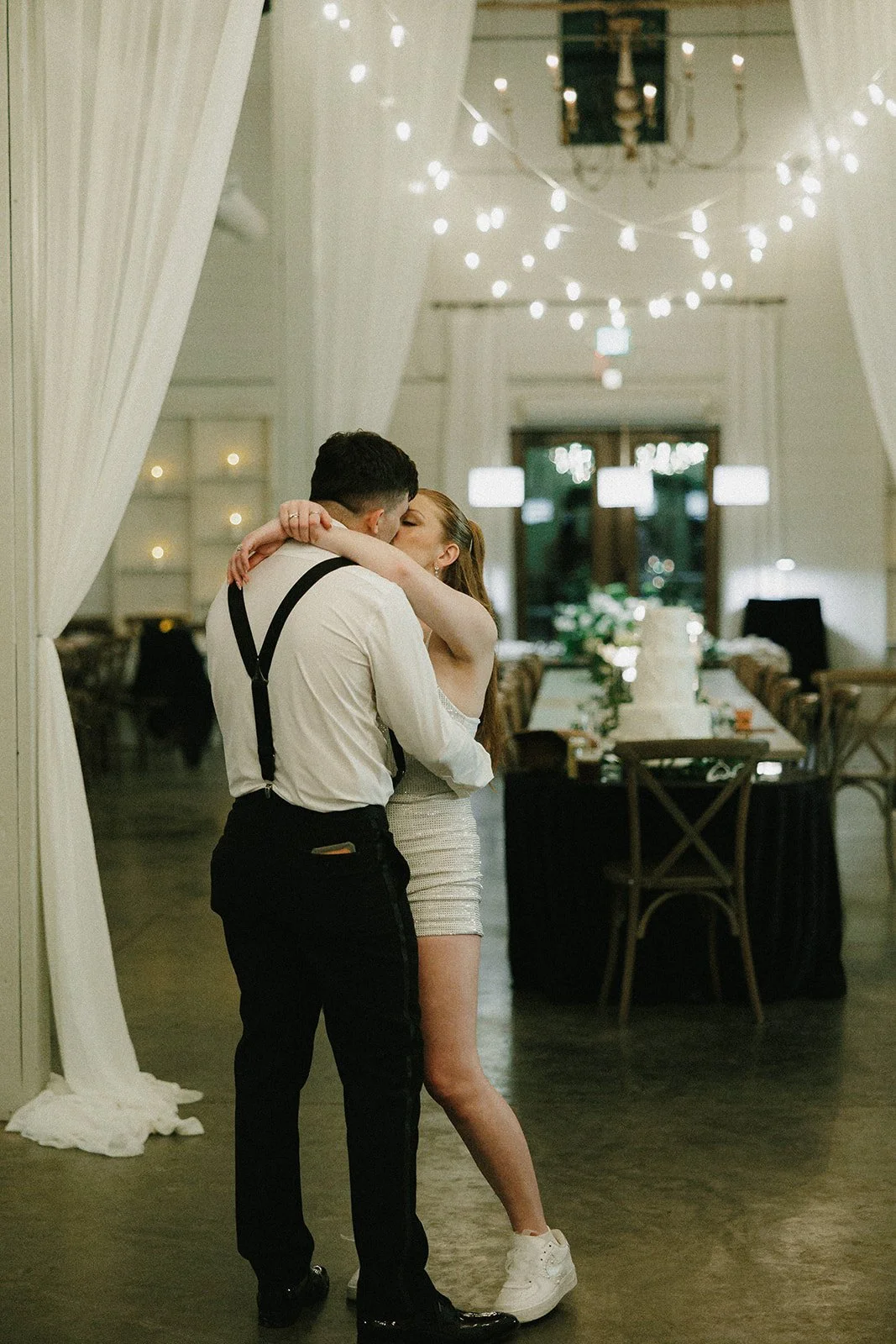 25-bride-in-a-sparkly-reception-dress-and-sneakers-kissing-the-groom-on.jpg
