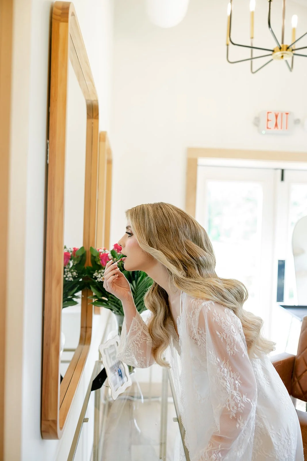 03-bride-in-a-lace-robe-putting-on-lipstick-in-the-bridal-suite-mirror-at.jpg