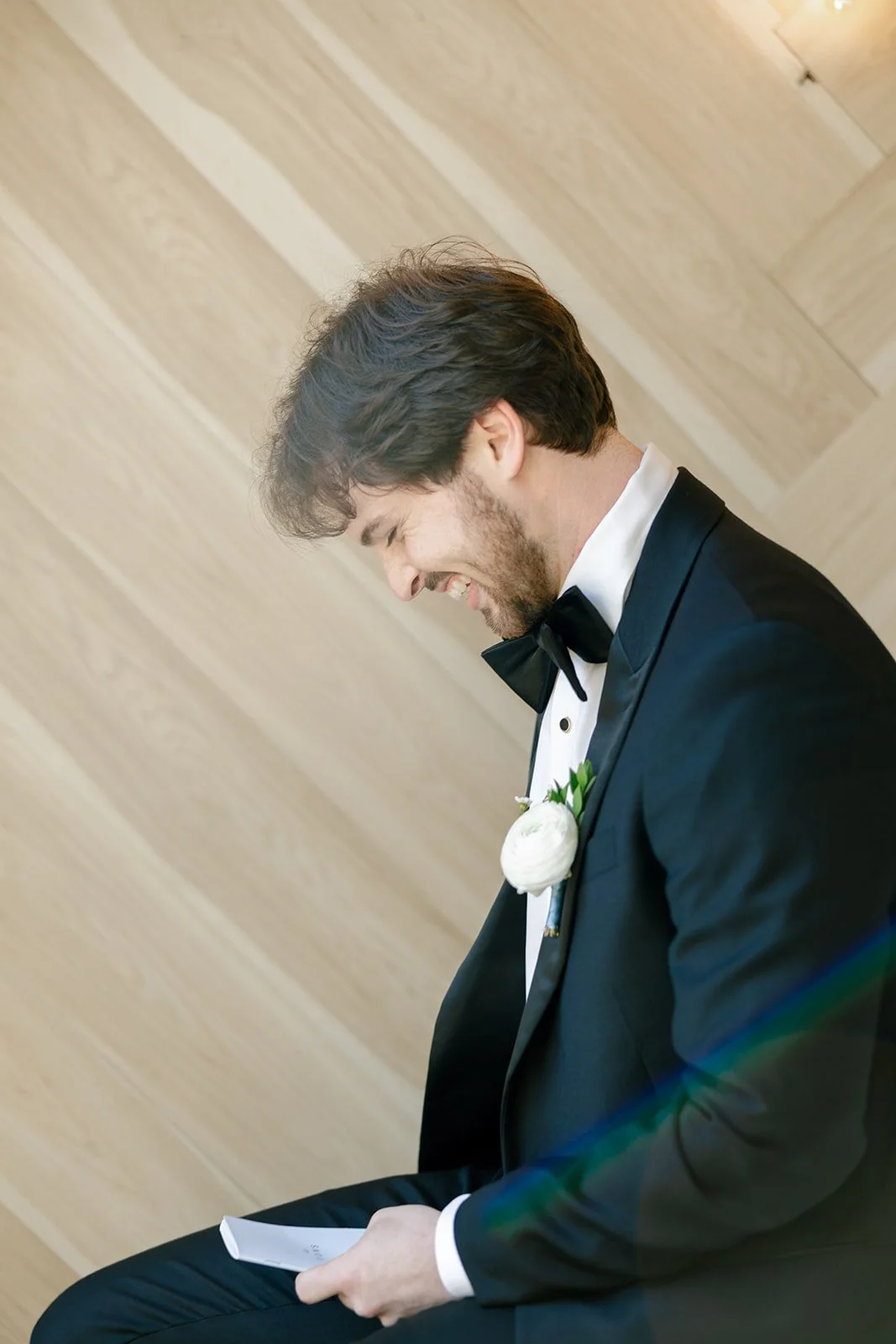 06-groom-laughing-as-he-reads-a-letter-from-his-bride-at-the-stables-at.jpg