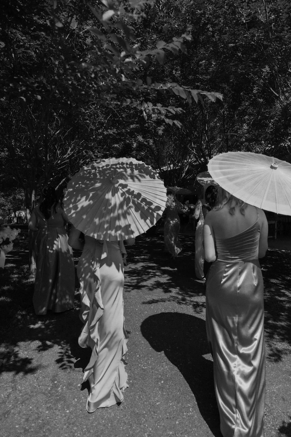 14-bridesmaids-walking-under-paper-parasols-through-dappled-shade-at.jpg