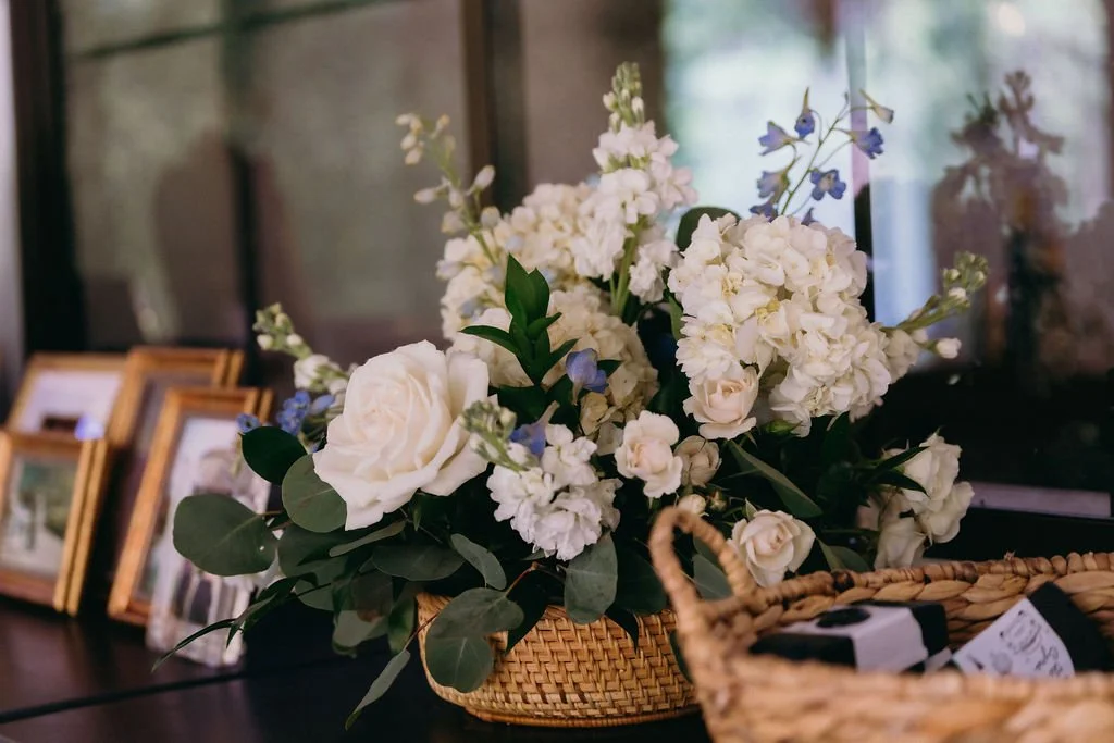 33-basket-arrangement-of-white-roses-and-stock-beside-framed-family-photos.jpg