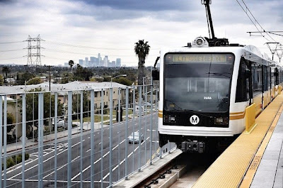 An Expo Line test train rests at the La Cienega station, with the downtown L.A. skyline in the distance. Photo by Steve Hymon/Metro via Wikipedia .
