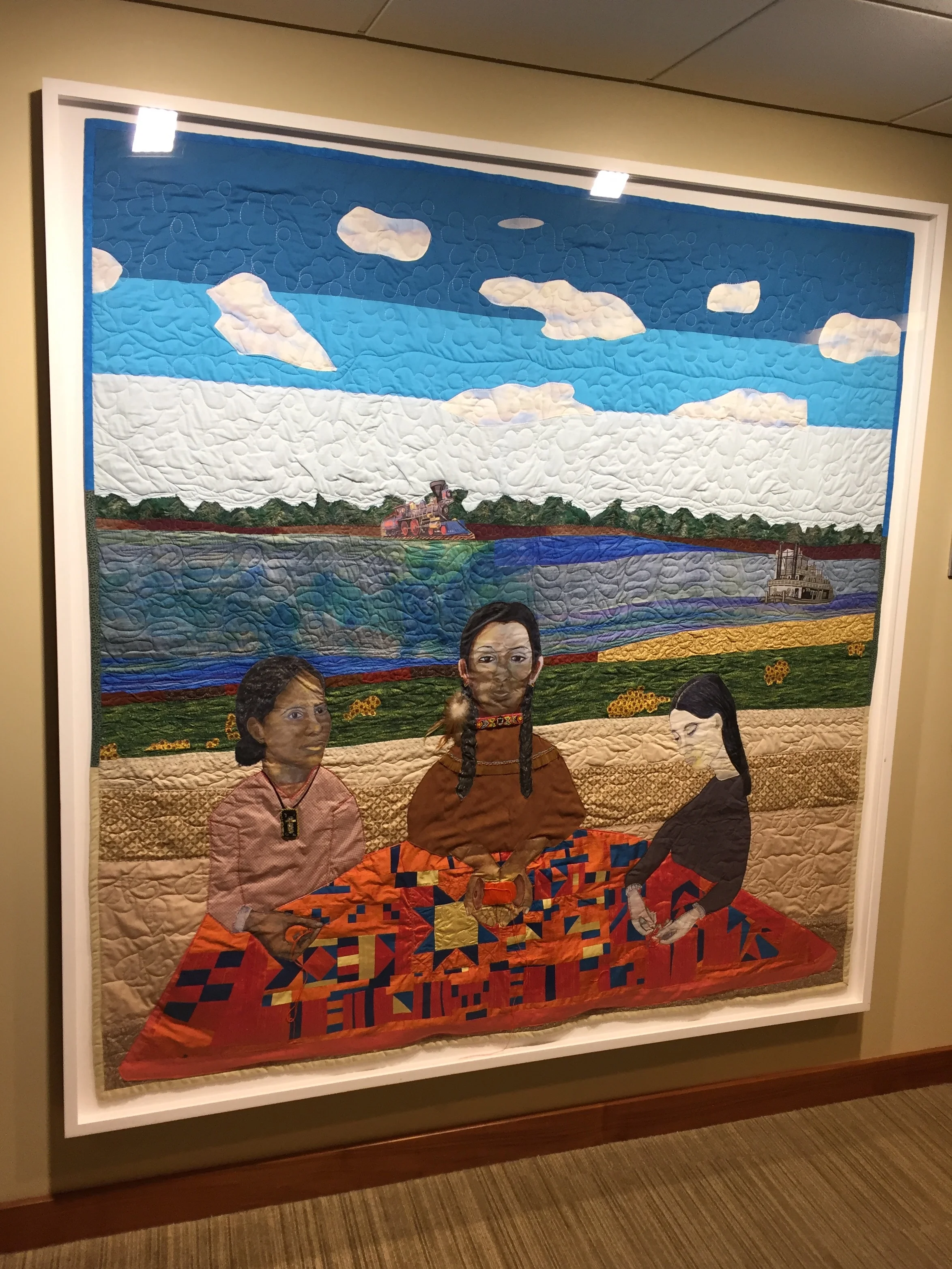 NedRa Bonds Connecting Threads, 2014 A beautiful quilt showing 3 women of different ethnicities all working together on a quilt.
