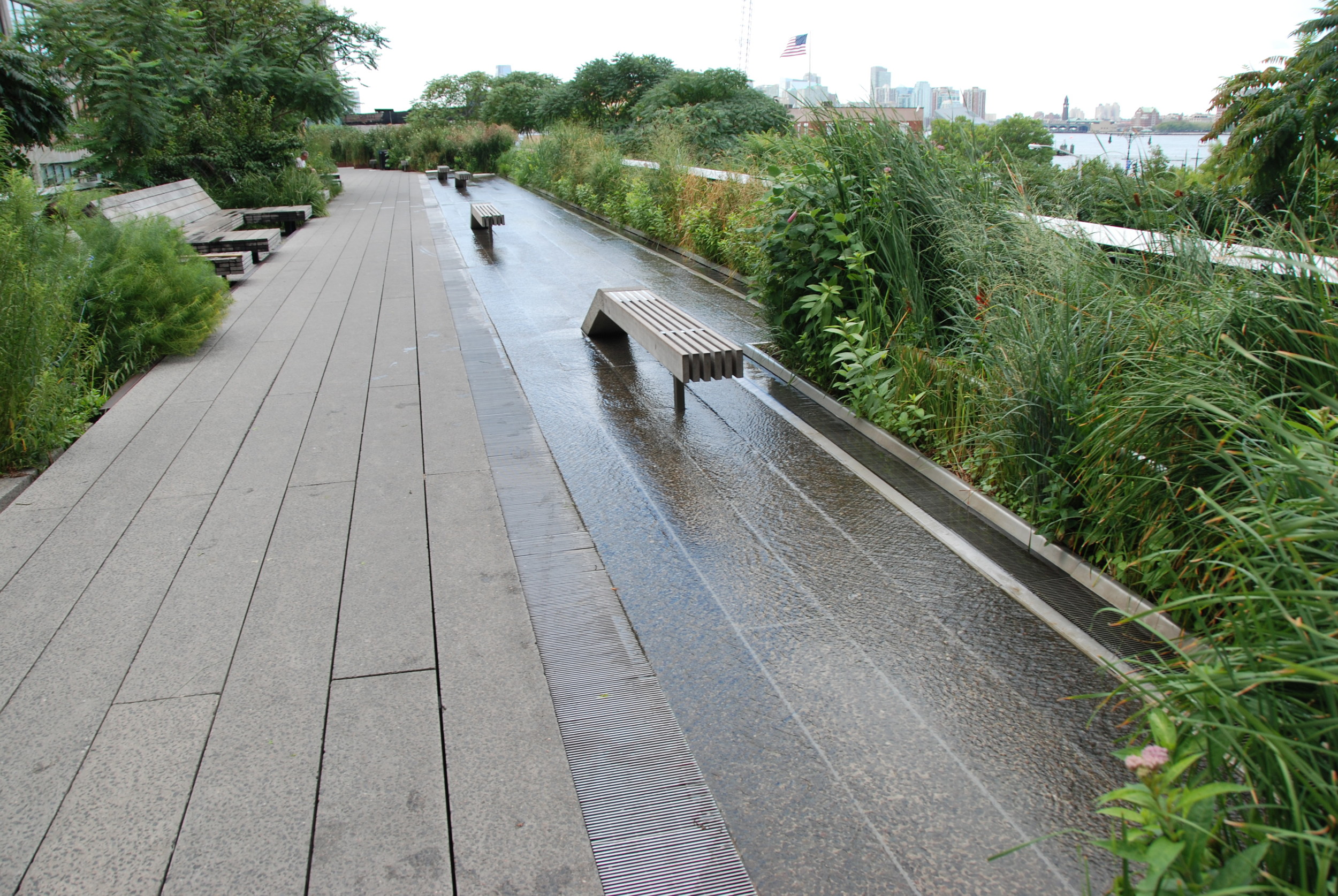 Tato část High Line patří mezi nejpopulárnější, a to nejen pro možnost procházky v tekoucí vodě. Jedná se o široký prostor (za zalení napravo se nachází další část High Line s další zelení) v blízkosti občerstvení, toalet a s možností využití lehátek (na levé straně fotografie), odkud můžete pozorovat řeku Hudson a New Jersey. (foto: Libor Hinčica)