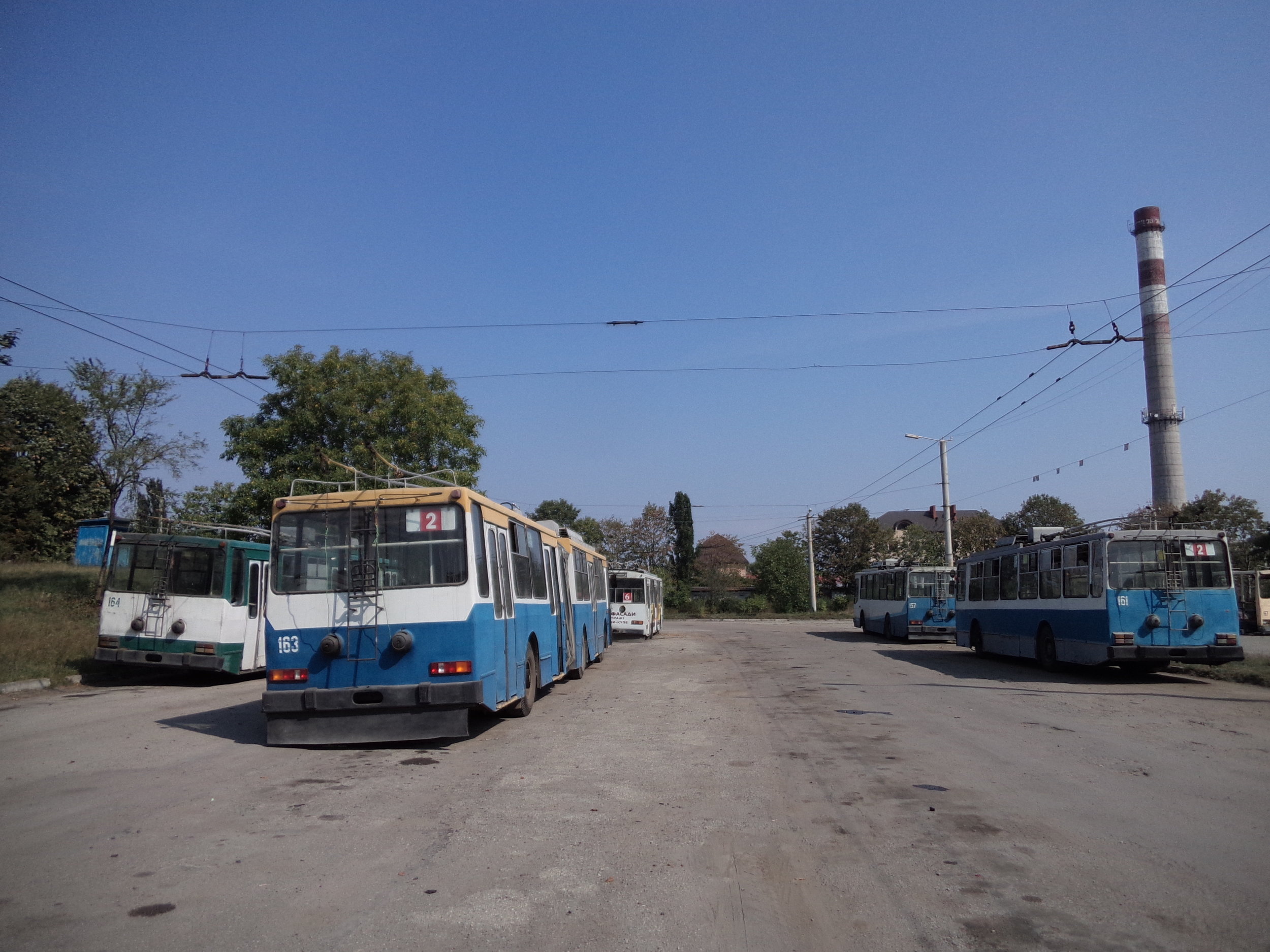 V polovině 90. let přišly do Ivano-Frankivsku čtyři článkové vozy JUMZ T1, které obdržely ev. č. 161–164. Vozům ev. č. 161 a 164 byla později odňata zadní část a po příslušných úpravách se z nich staly sólo trolejbusy vedené pod stejnými ev. č., avšak už jako přeznačený typ JUMZ T1P. Oba tyto zkrácené vozy jsou přitom na snímku přítomny. Z dvou zbývajících článkových vozů jezdí už jen jeden, a to ten nesoucí ev. č. 163. Na pravé straně vzadu si ještě povšimněme vozu s ev. č. 157. Jedná se o jeden ze sedmi krátkých vozů (ev. č. 157, 165–170) typu JUMZ T2, které do Ivano-Frankivsku zavítaly ve stejném období jako vozy článkové. Dnes už jsou vypravovány jen tři z nich. 