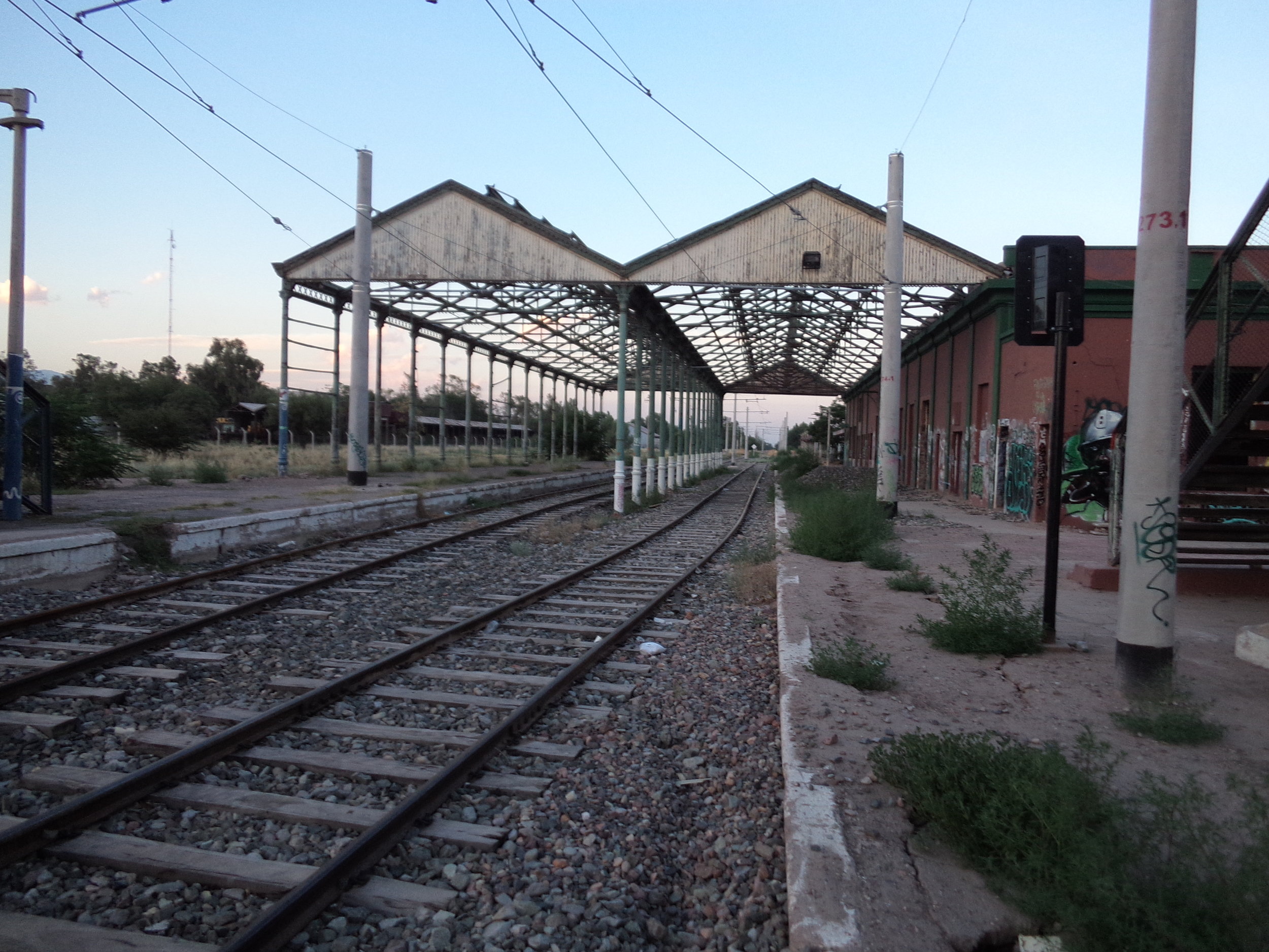 Průjezdné nádraží Mendoza patřilo dráze zvané Ferrocarril General San Martín (rozchod 1 676 mm). Končily zde mimo jiné i vlaky z Buenos Aires, ze kterého se sem dalo dostat z obou možných směrů, neboť Mendozu obklopoval jakýsi železniční okruh, jak už ostatně vyplynulo z jednoho z předchozích komentářů. Zaústěna sem byla i větev dráhy Ferrocarril General Belgrano (rozchod 1 000 mm), byť hlavní stanice této dráhy byla v Mendoze (přesněji řečeno na území Gran Mendozy) někde jinde, a sice asi 3 km východně od této (tj. napravo od snímku). 