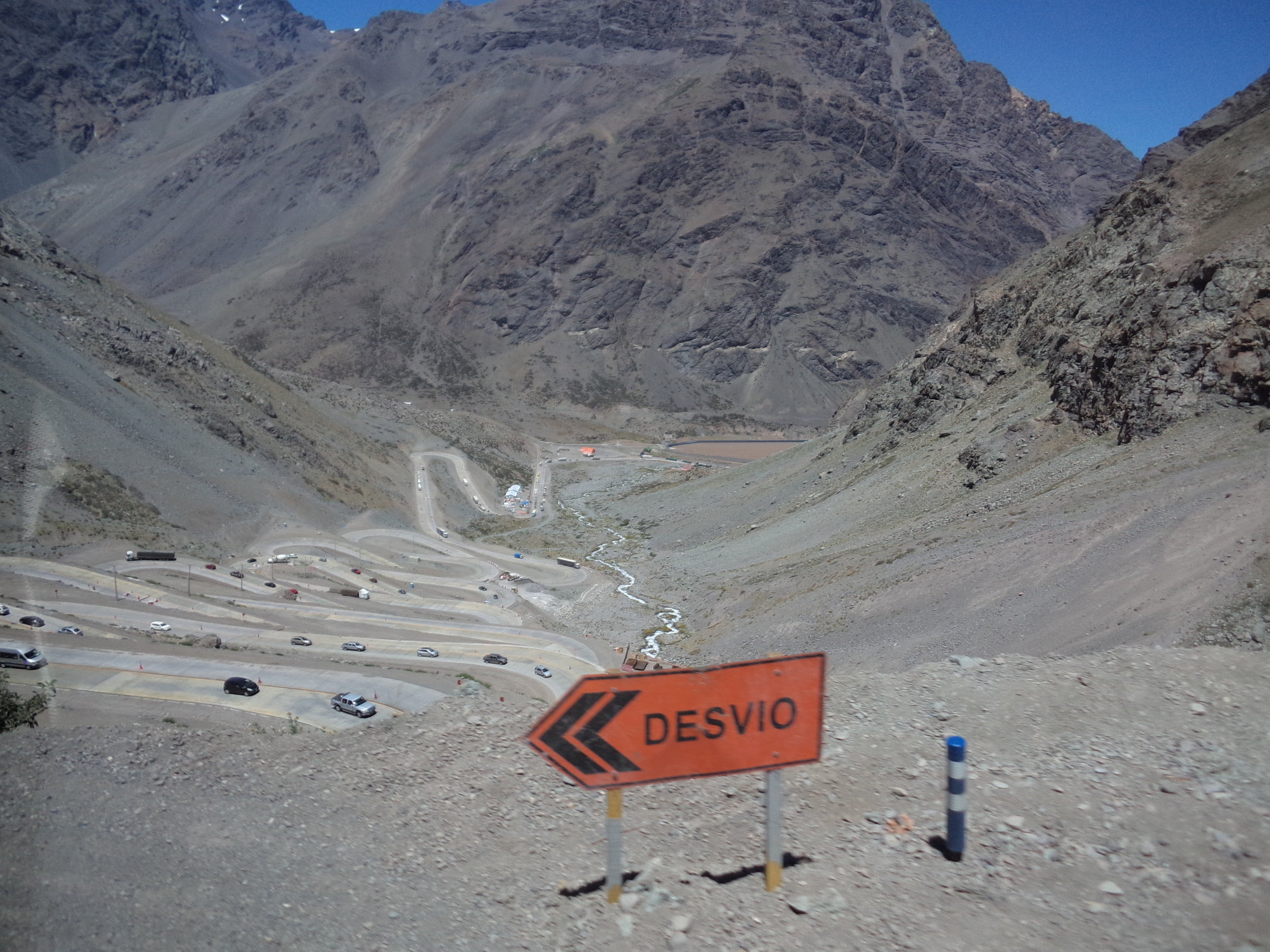 Překonávání takto náročného výškového rozdílu se transandská železnice spojující chilské město Los Andes s argentinskou Mendozou nevyhnula, cestu si ovšem razila delší trasou (a sice vlevo mimo záběr) než dnešní silnice č. 60. Je velká škoda, že 248 km dlouhá trať, kterou stavěly pod taktovou anglické společnosti od konce 80. let 19. století na obou stranách argentinské-chilské hranice tisíce dělníků (obě země se přitom v té době ještě dohadovaly o podobu svých hranic!), vydržela v provozu jen sotva tři čtvrtstoletí (1910 – 1984). O jejím konci rozhodly roku 1984 rozsáhlé laviny, které ji na řadě míst poškodily. Argentinská strana sice své poškozené úseky částečně opravila, chilská ale nikoli, a tak se od té doby už nejezdí. Na chilské straně je pro potřeby nákladní dopravy v provozu jen úsek Los Andes (km 248) – Río Branco (km 214), neboť v Río Branco je odbočka do měděných dolů společnosti Codelco. Záběr byl pořízen na chilské straně na jednom z tzv. „ šneků “ , neboli serpentinách. Dodejme ještě, že ve městě Los Andes museli cestující kvůli odlišným rozchodům tratí přestupovat. 
