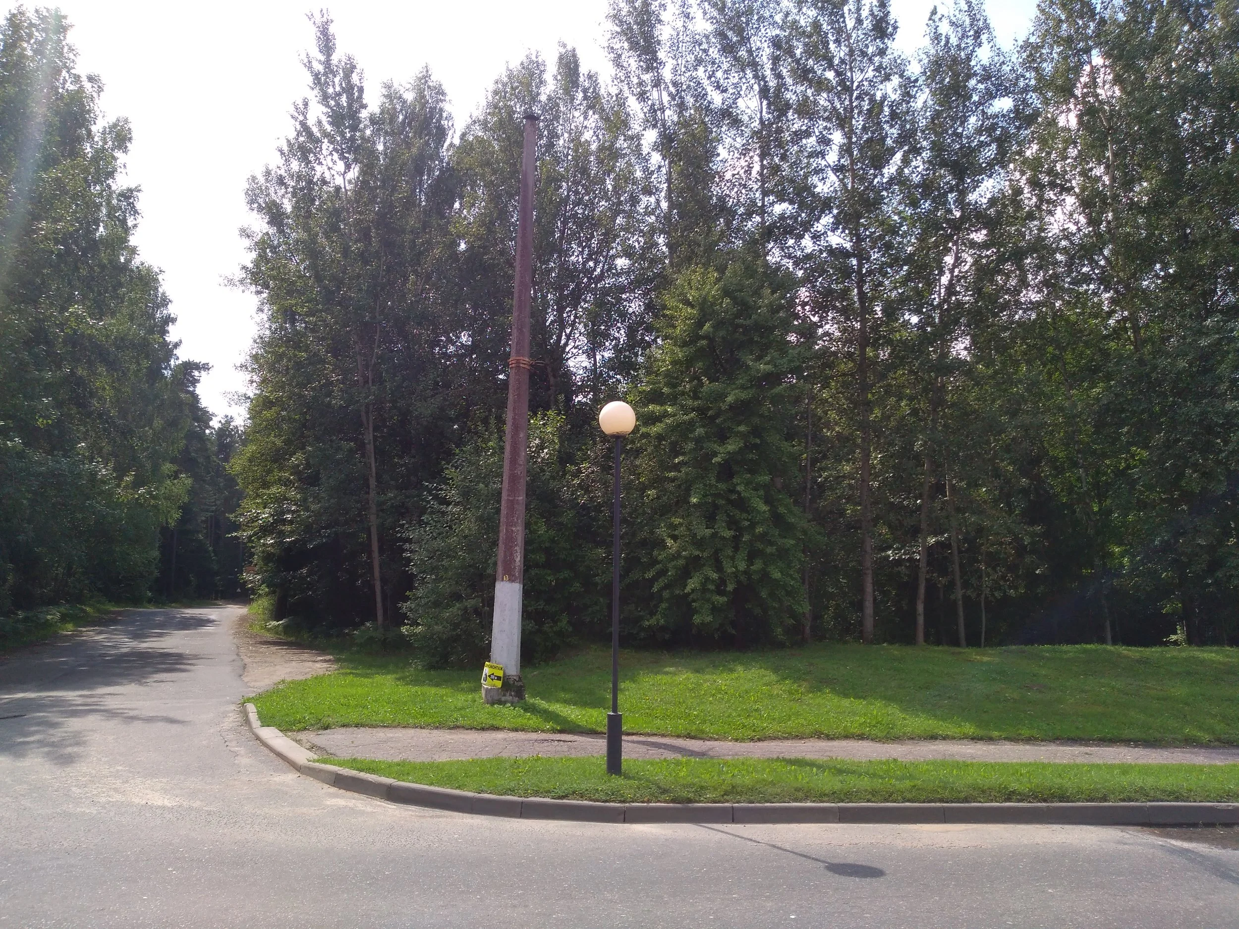 Osamocený sloup nese nosné lano, které mizí mezi stromy. Cesta dozadu vede ke garážím, které jsou vzdálené asi 200 m. Zejména za zimních dlouhých nocí musí být procházka k autu dobrodružná...