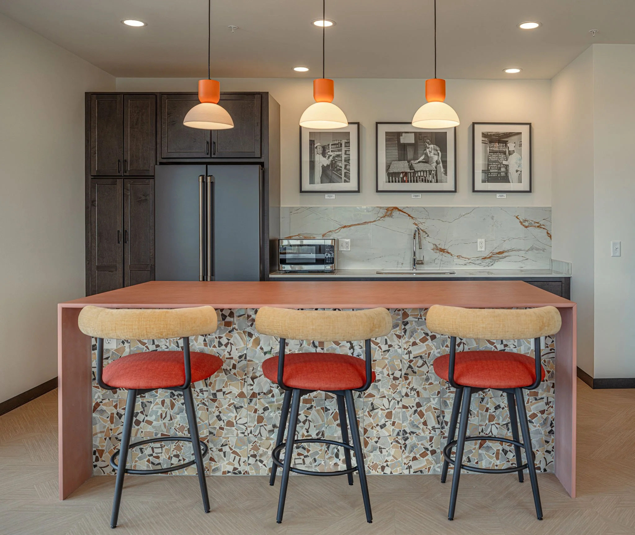 Common area kitchen with pendant lighting, stools and kitchenette