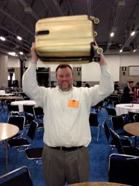 Brian Jensen hoists his Pressure Chamber winner's trophy, a golden suitcase.