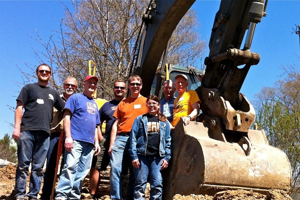Roger, pictured center wearing an orange shirt and sunglasses, worked with his ManKind Project crew on a Habitat for Humanity service project in April 2015. To his disappointment, he did not get to drive the backhoe.