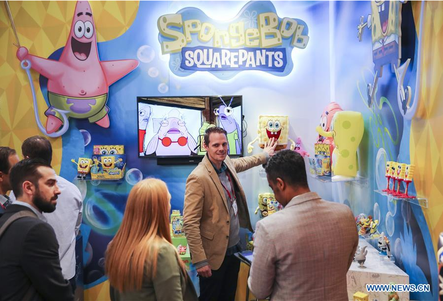 Visitors look at toy products of SpongeBob at the booth of Alpha Group Co., Ltd., a major animation, toy and entertainment player from Guangdong Province in southern China, during the 116th Annual North American International Toy Fair at the Jacob K. Javits Convention Center in New York, the United States, on Feb. 19, 2019. Chinese toy manufacturers, which produce around 75 percent of global toys each year, are rising up the value chain from the original role as contract manufacturers to designers and makers of their own brands. (Xinhua/Wang Ying)