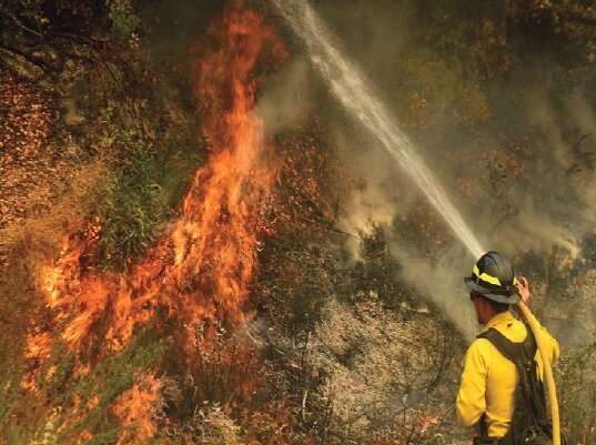A firefighter puts out a hot spot in northern California. The El Dorado fire was caused by a gender reveal party.