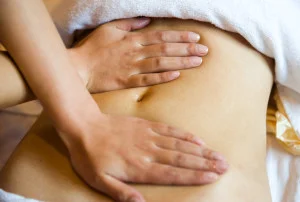 Person's hands on a clients belly massaging it.