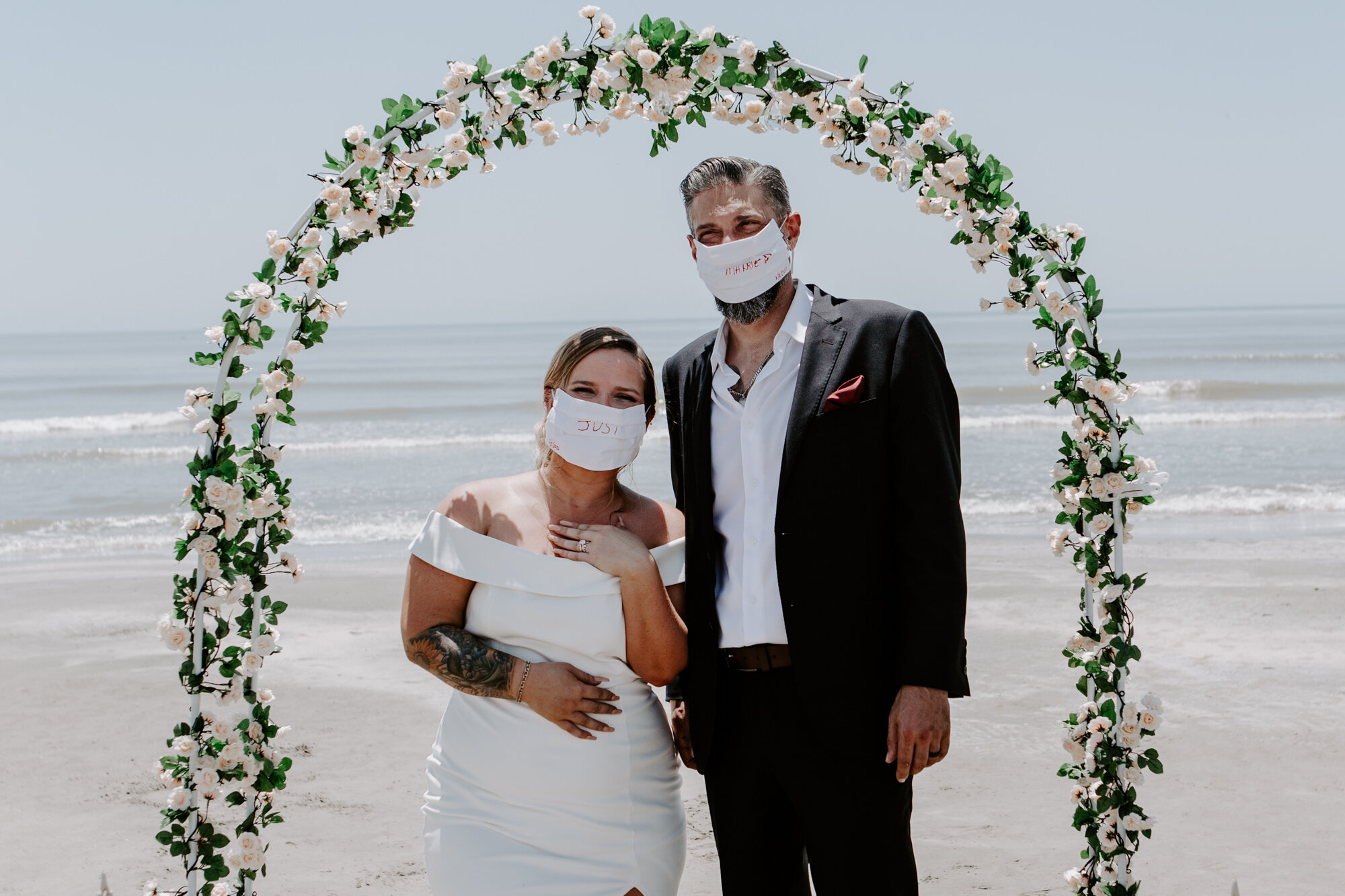Ceremony. Micro Wedding (Elopement) COVID-19 pandemic bride and groom wear just married masks on the Beach