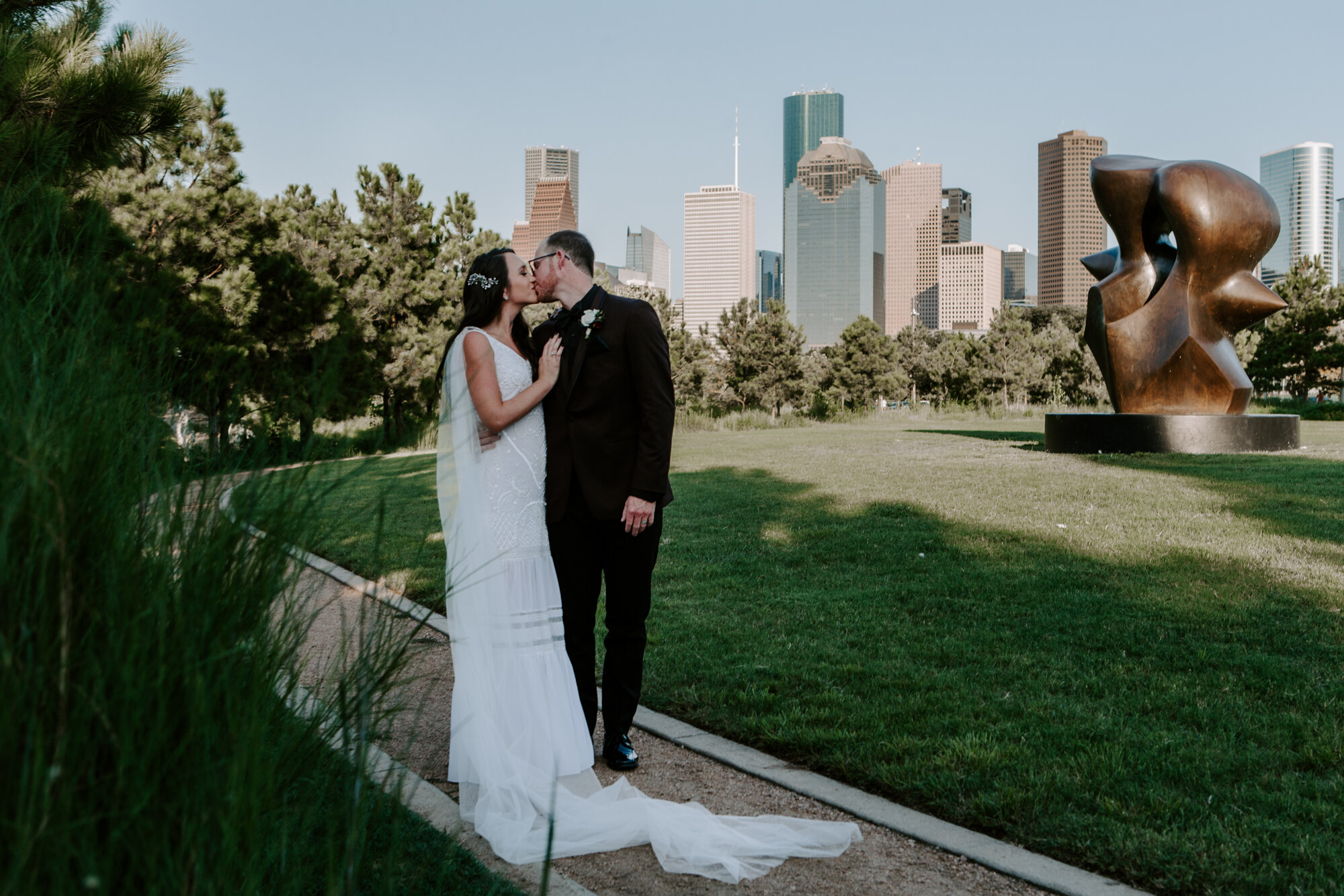 Bride and groom wedding portraits with downtown skyline view at Buffalo Bayou Park