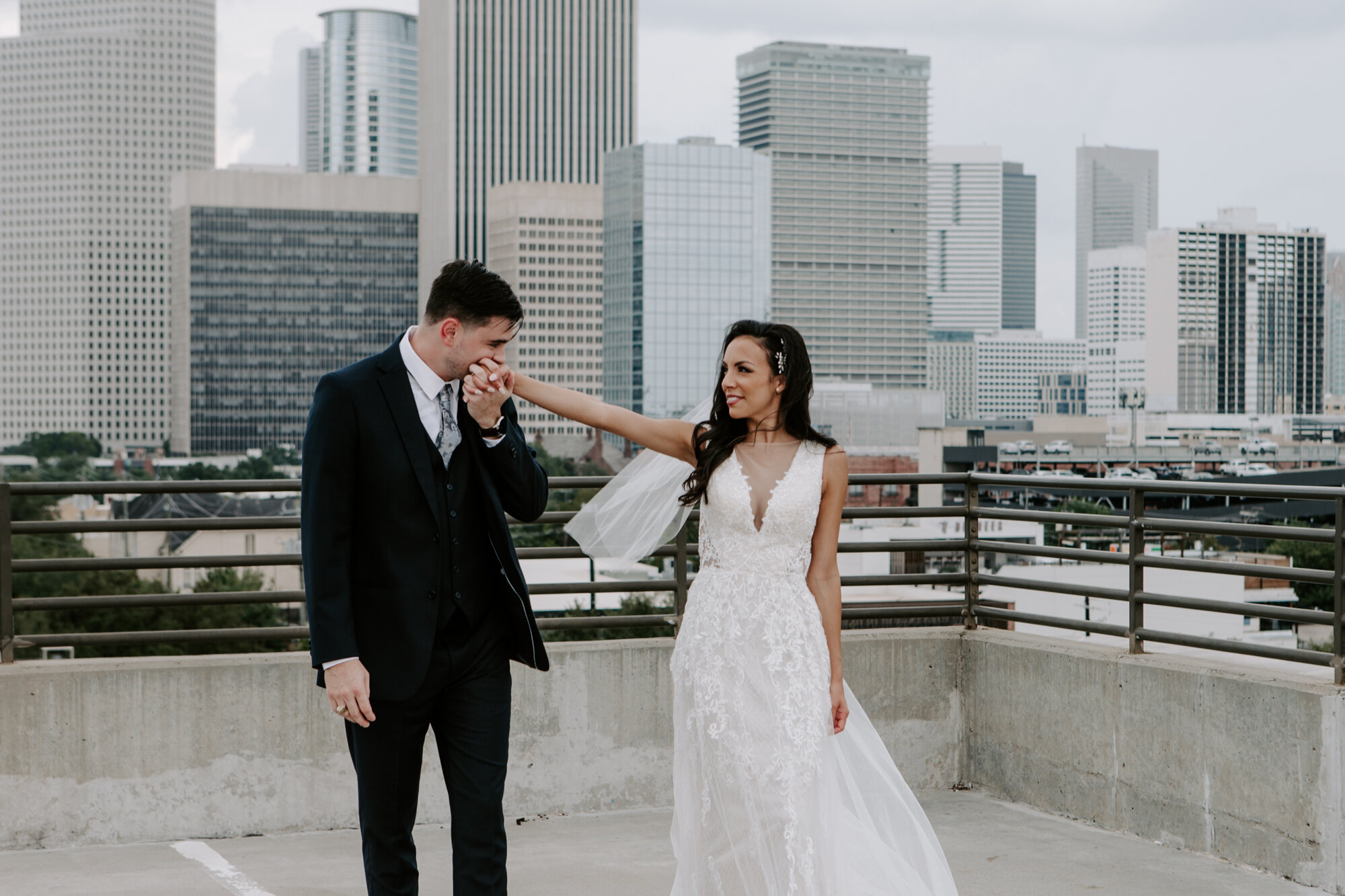 Vivacious Wedding groom kisses bride's hand first look in Midtown with downtown skyline view