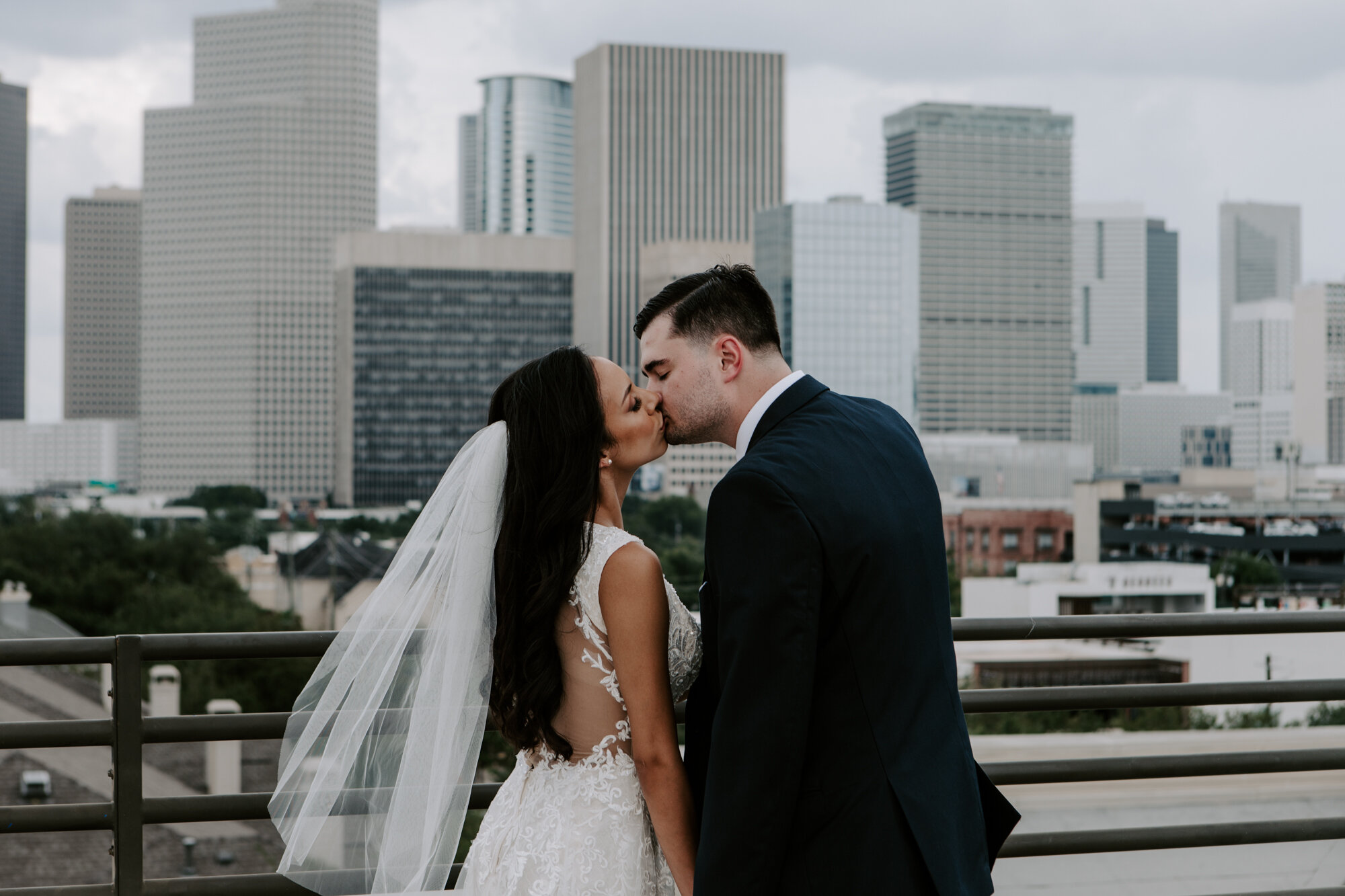 Vivacious Wedding bride and groom kiss first look in Midtown with downtown skyline view