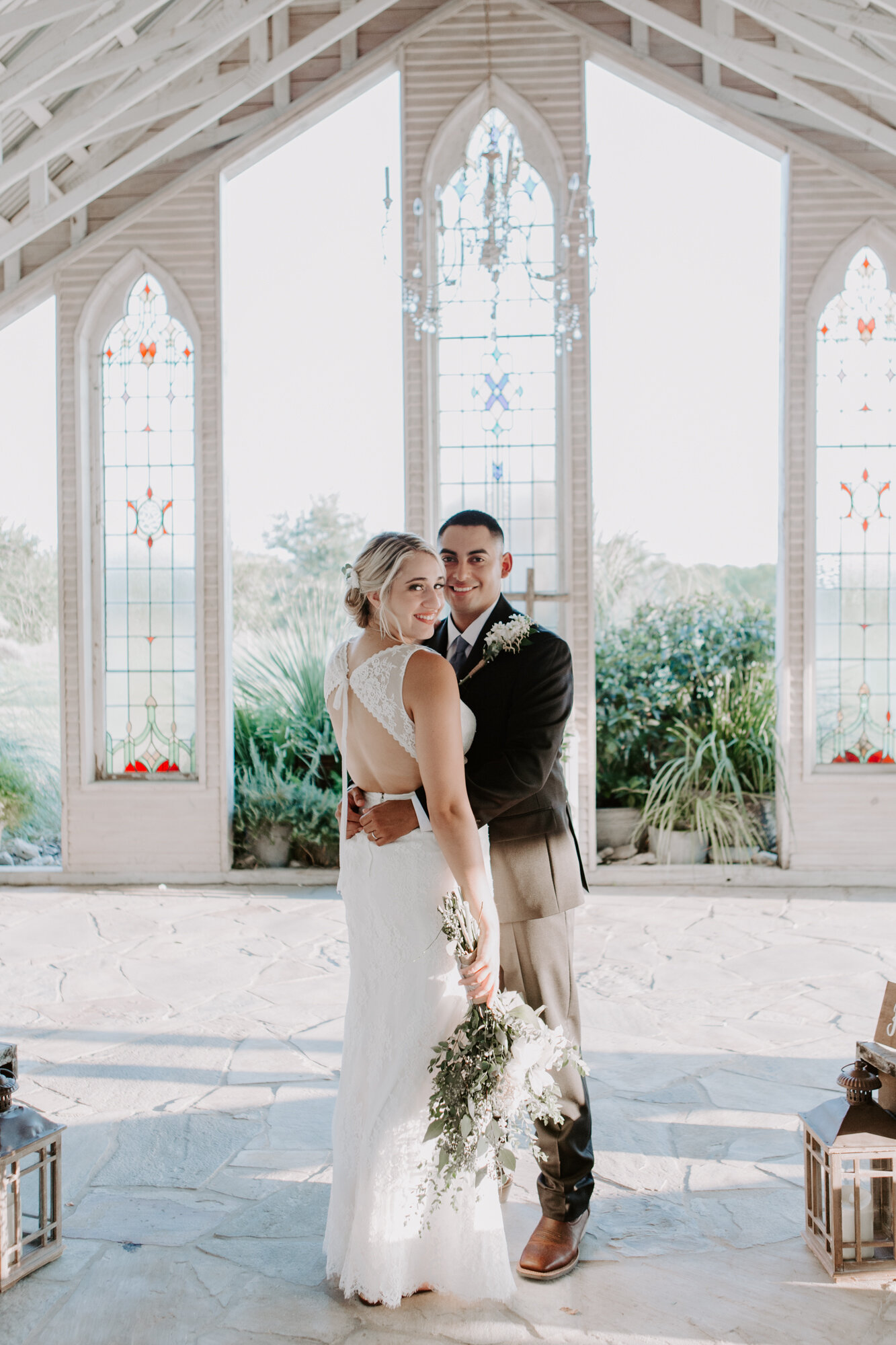 Bride and groom hug in the chapel. Radiant Bohemian Hill Country Wedding at Gruene Estate in New Braunfels, TX