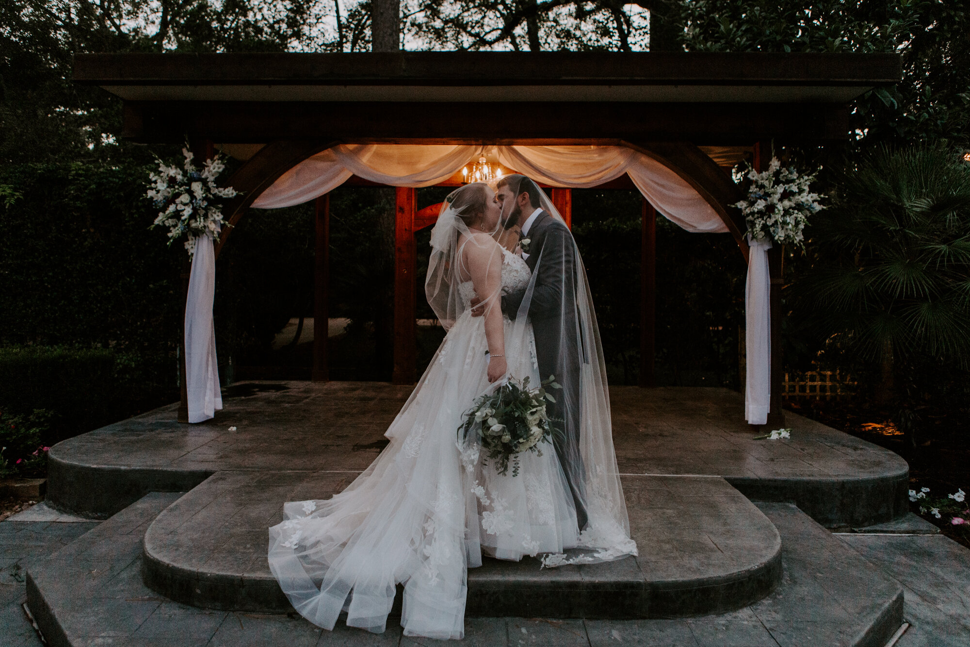 Bride and groom kissing under veil in the gazebo. Romantic Sunset Wedding at Shirley Acres