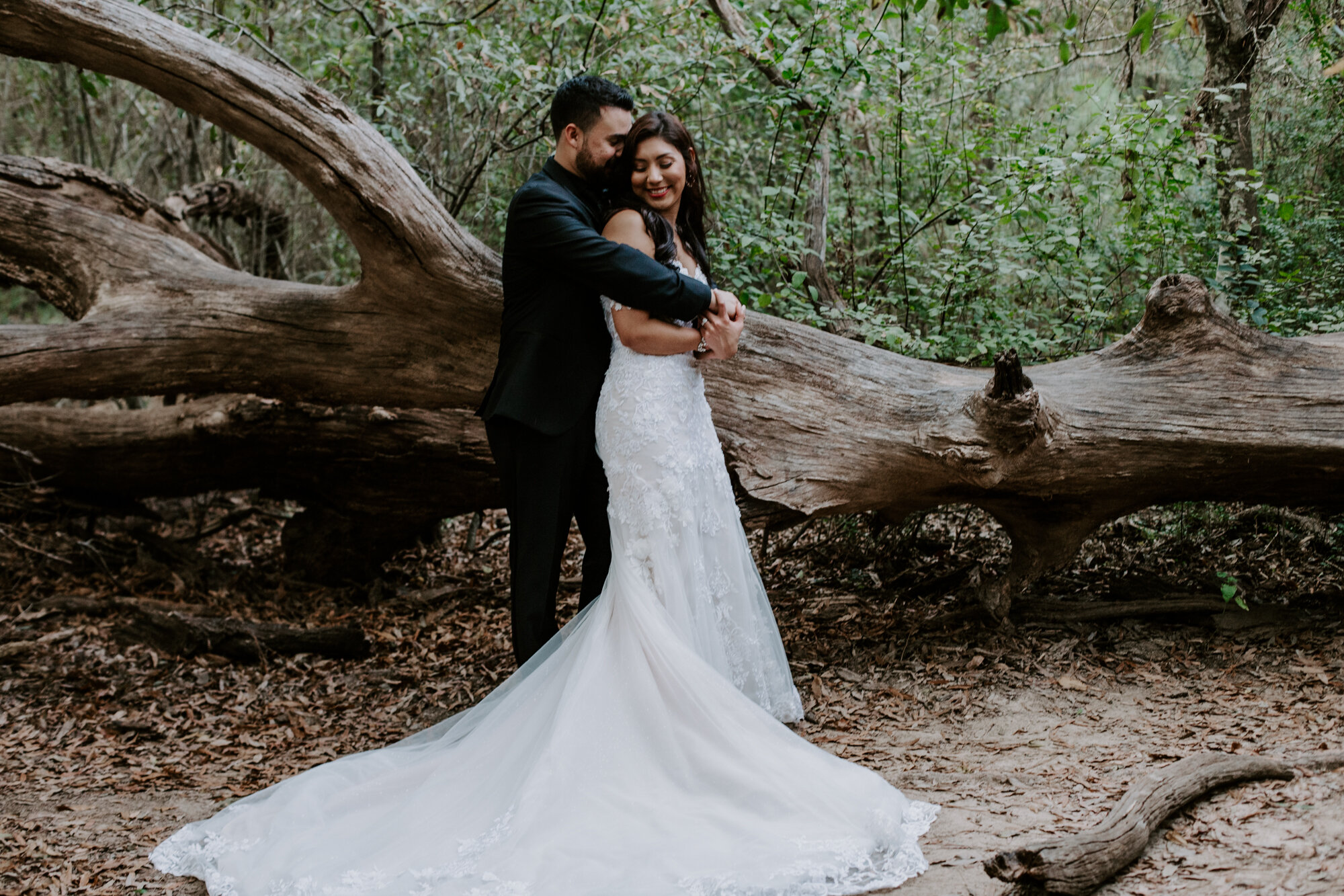 Hugging by the fallen tree. Trash the Dress Bride and Groom Photo Session at Houston Arboretum and Nature Center