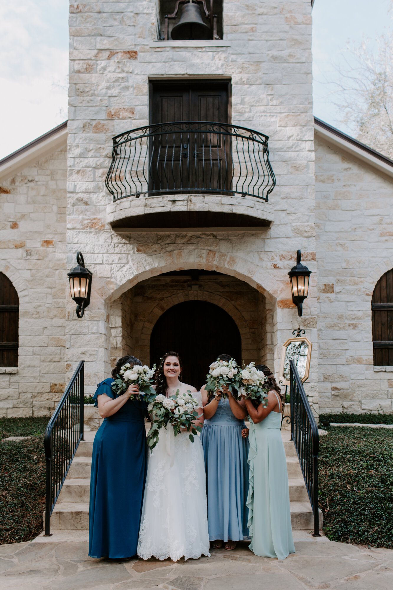 Bride ad bridesmaids in front of the bell tower. Fairy Romantic Wedding at Magnolia Bells in Magnolia, TX