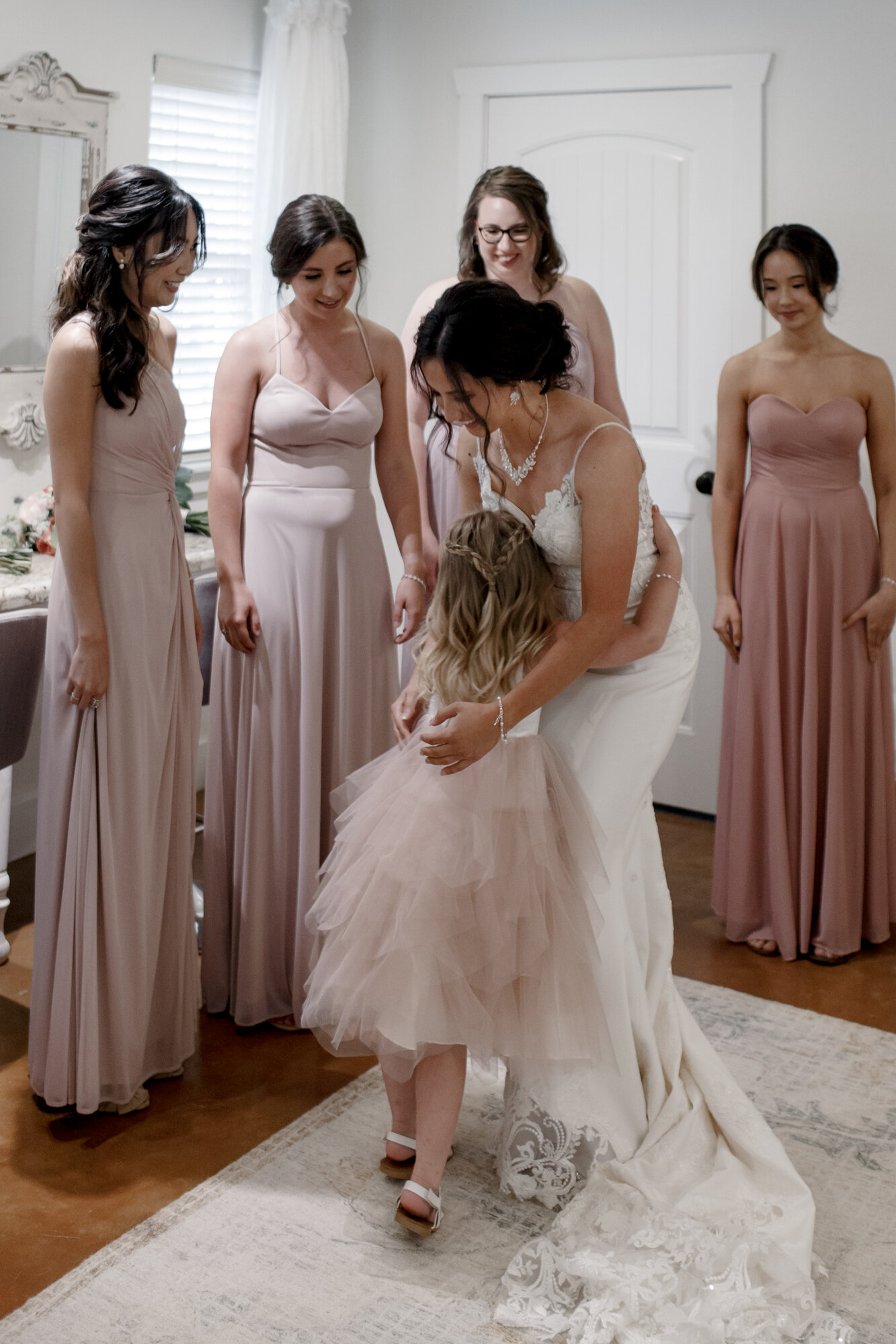 Bride getting ready hugging flower girl. Romantic Chic Country Wedding at Rustic Luxury Balmorhea Events&nbsp;Venue in Magnolia, TX