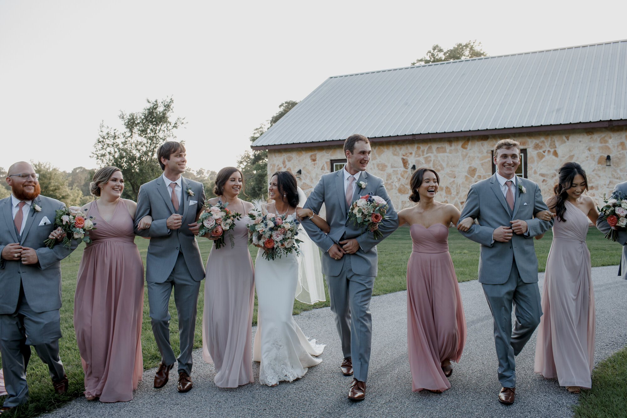 Bride and groom walking with bridal party. Romantic Chic Country Wedding at Rustic Luxury Balmorhea Events&nbsp;Venue in Magnolia, TX