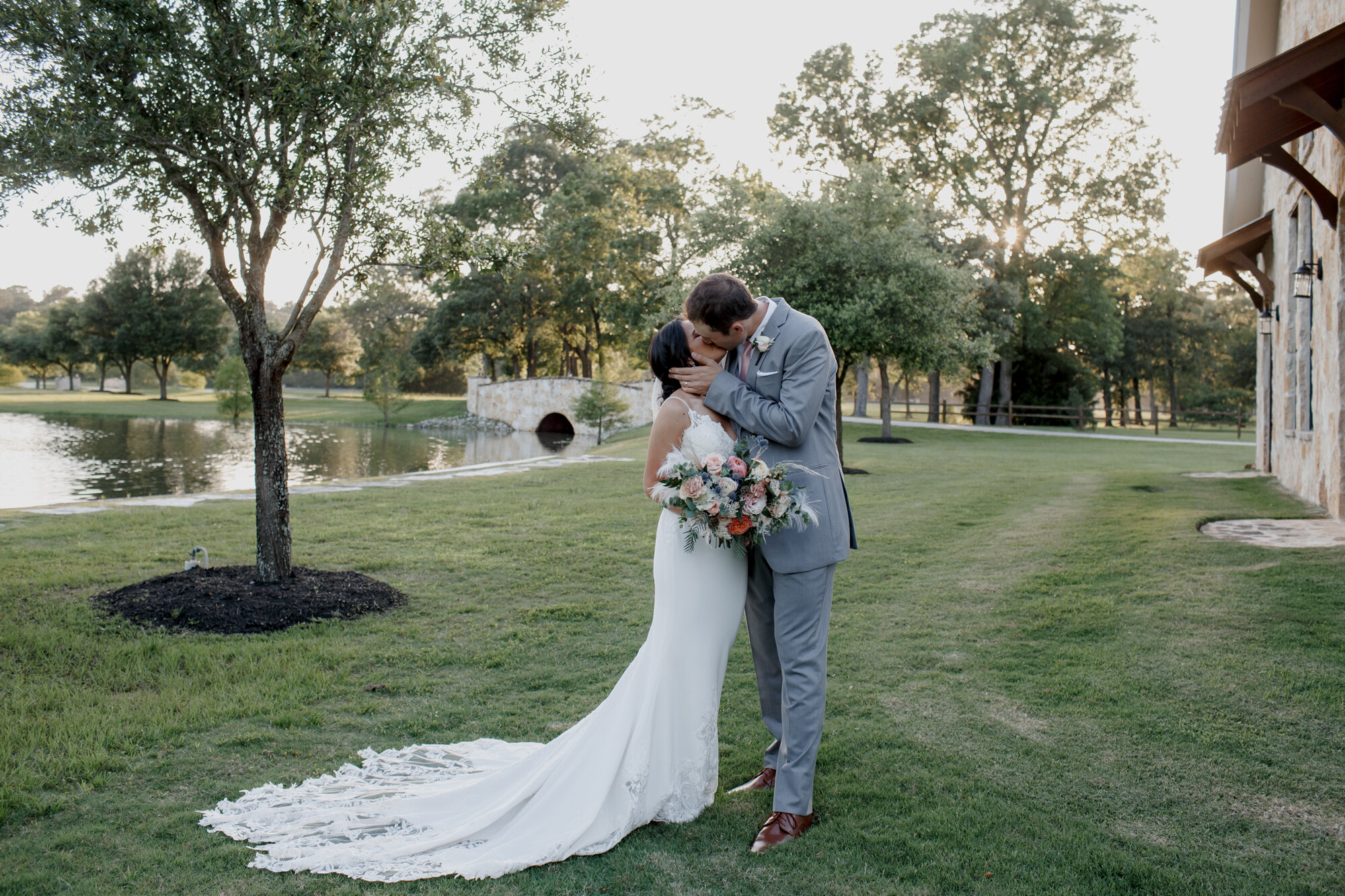 Bride and groom kissing by the lake. Romantic Chic Country Wedding at Rustic Luxury Balmorhea Events&nbsp;Venue in Magnolia, TX