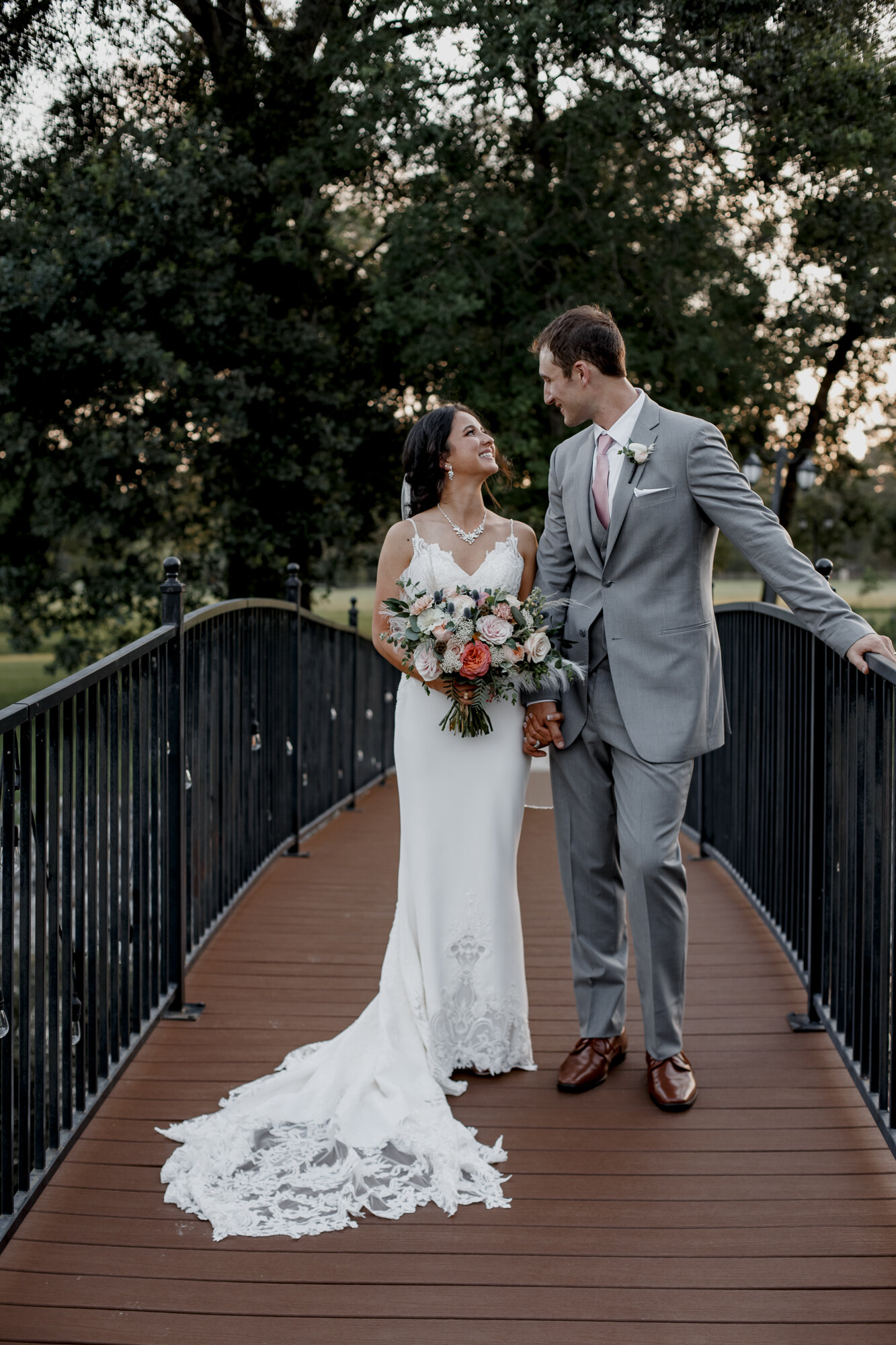 Bride and groom standing on the bridge looking at each other. Romantic Chic Country Wedding at Rustic Luxury Balmorhea Events&nbsp;Venue in Magnolia, TX